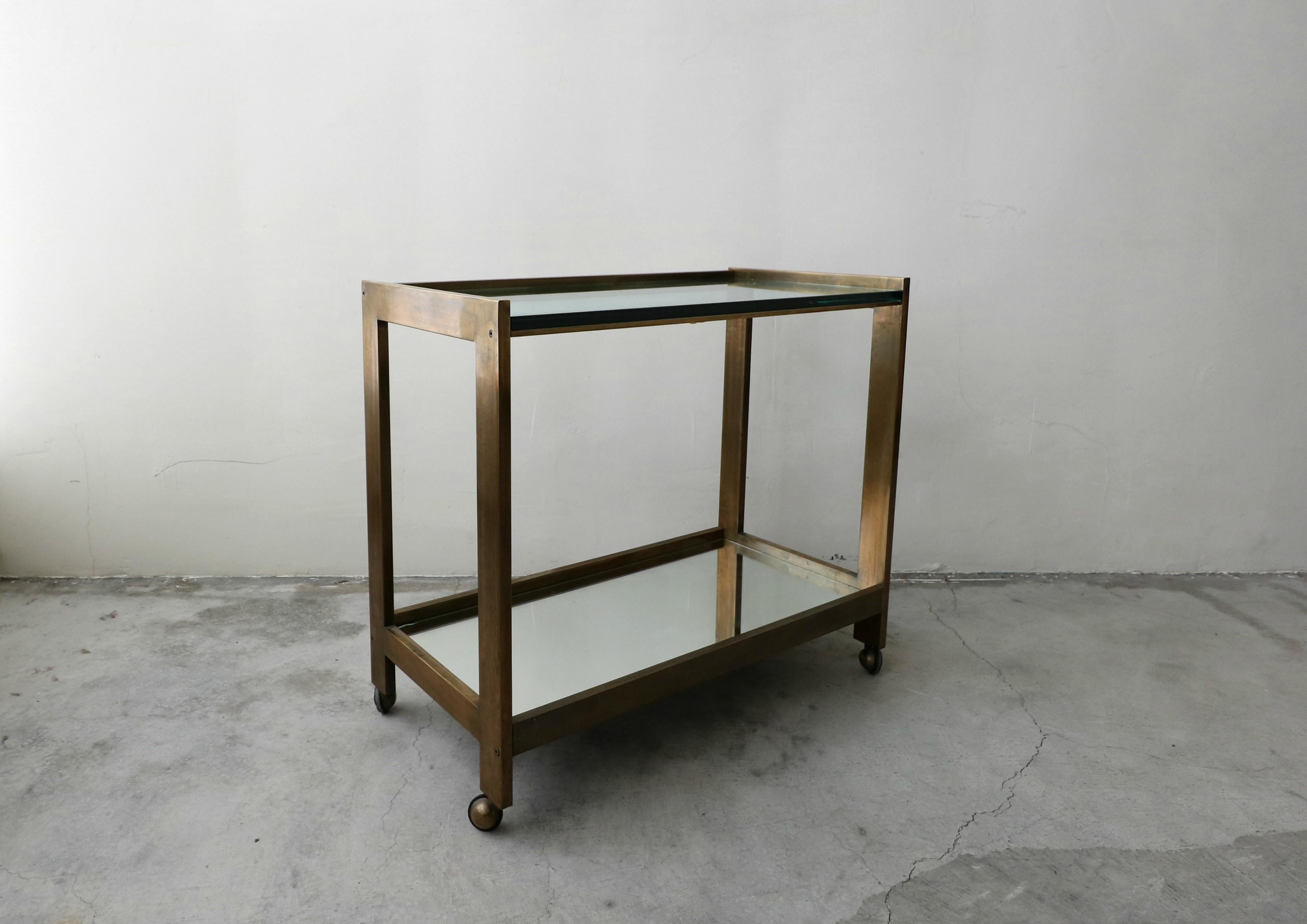An entertainer's dream, simple yet sophisticated. A stunning, high quality bronze, glass and mirror midcentury bar car. The transparency of this piece makes it perfect in most any space. With two tiers, the top one glass and the bottom one mirror.