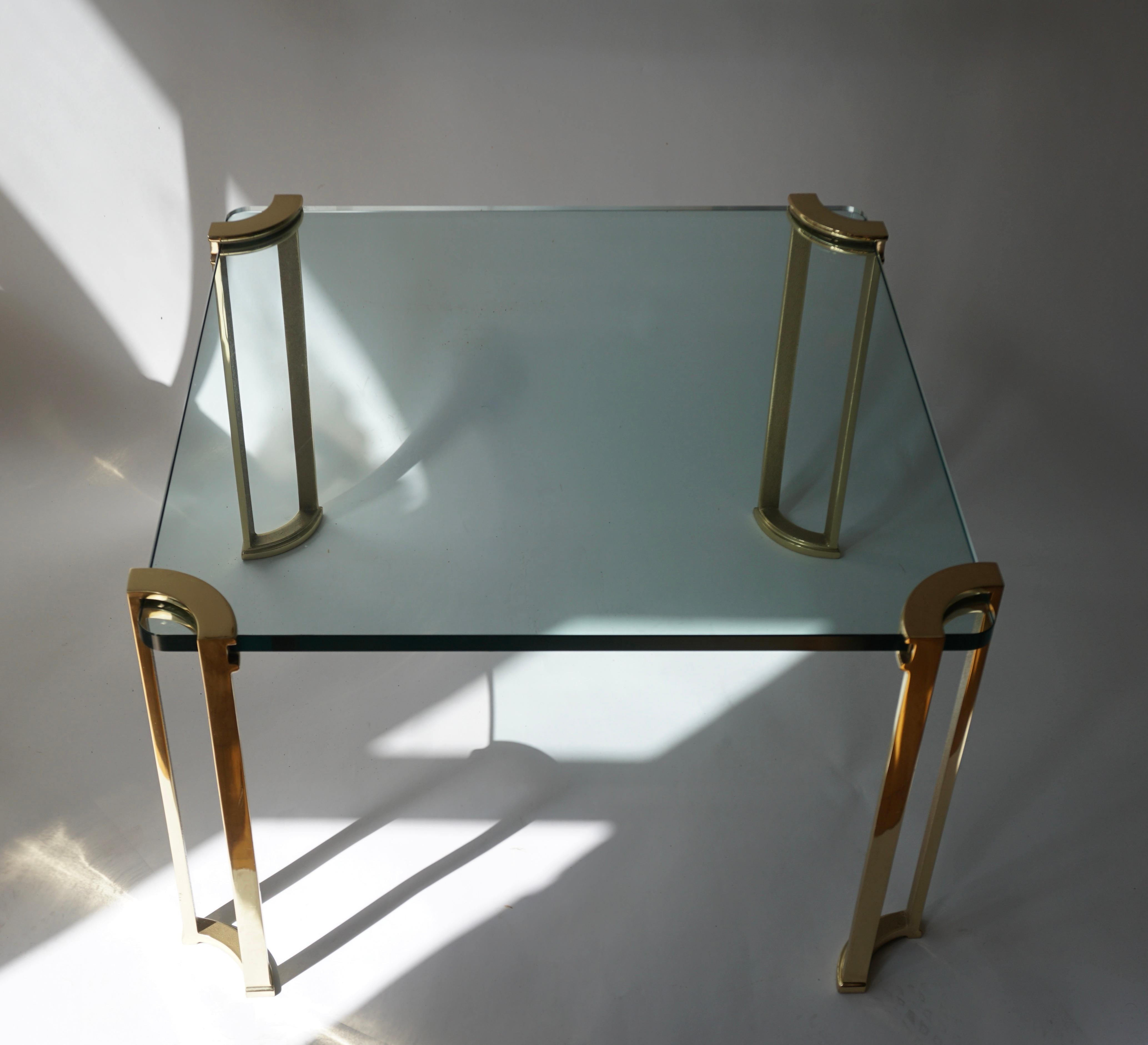 Cette table d'appoint ou de cocktail en bronze et en verre datant du début des années 1970 est dotée d'un plateau en verre et de pieds en bronze massif avec des détails architecturaux.

