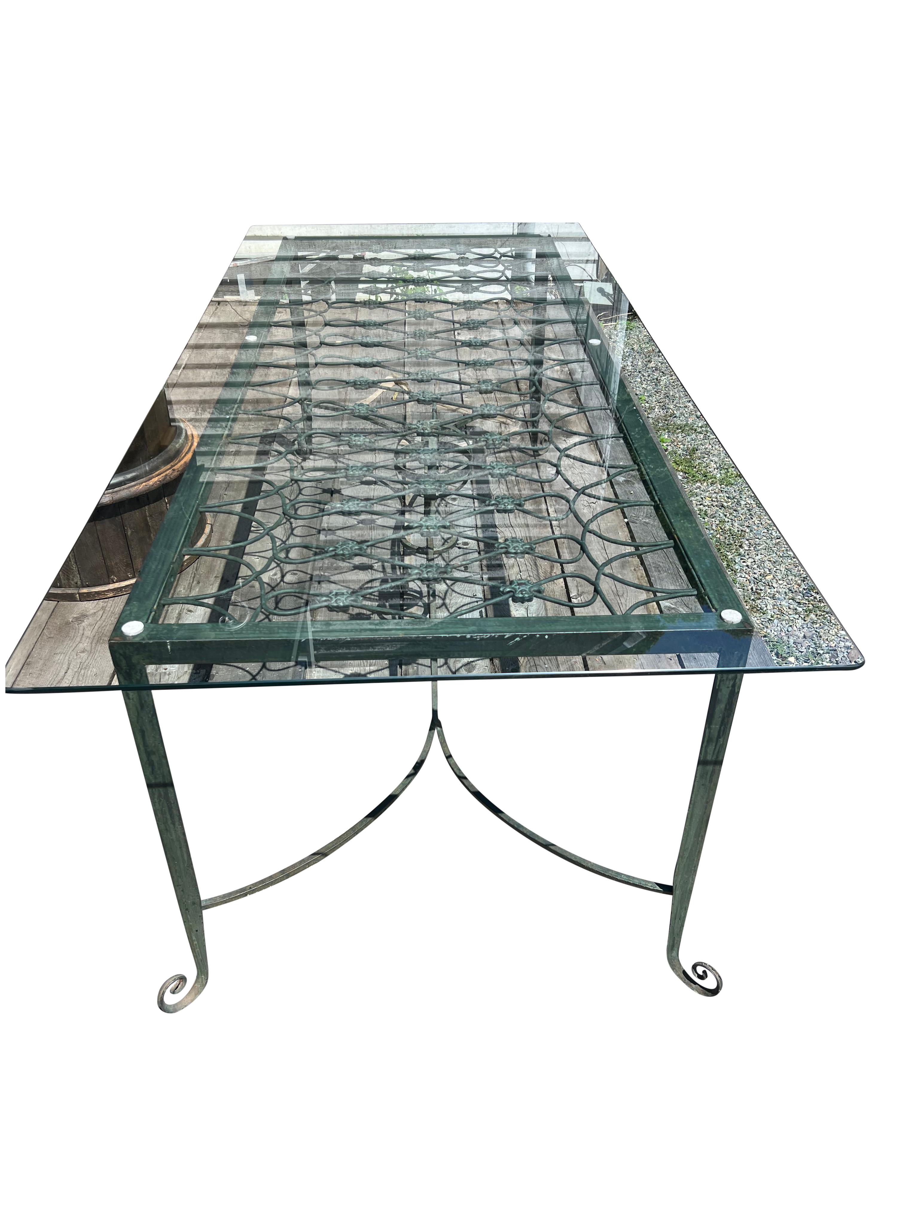 With rectangular glass top over a grate, raised on tapering legs with scrolled feet all joined by a stretcher with central orb.