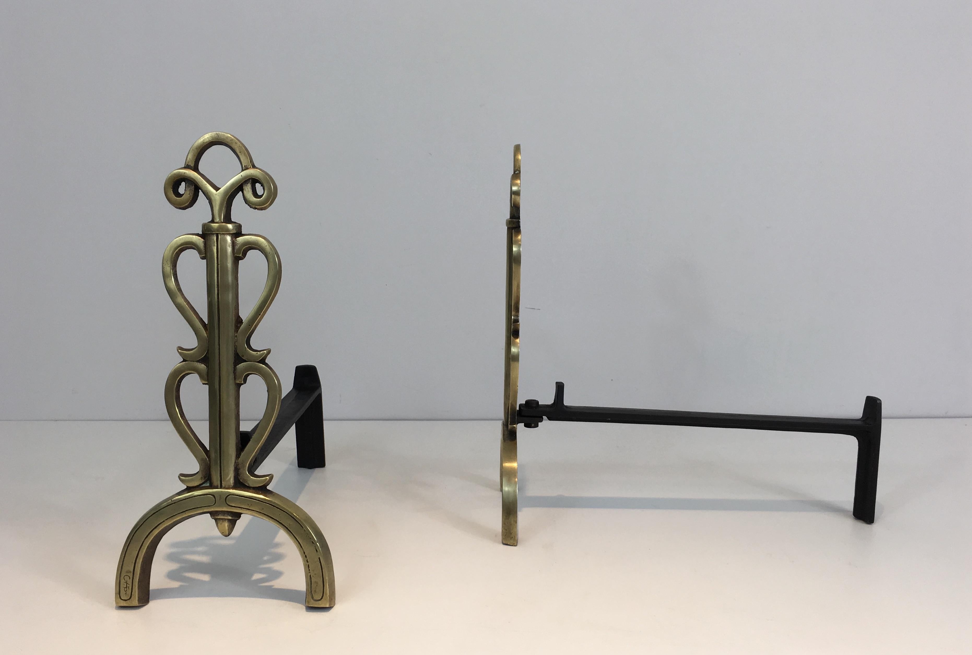 This pair of andirons is made of bronze and iron. They are French, from the 1930s, in the style of Raymond Subes or Jules Leleu. They are typical from the Art Deco period. They are signed.