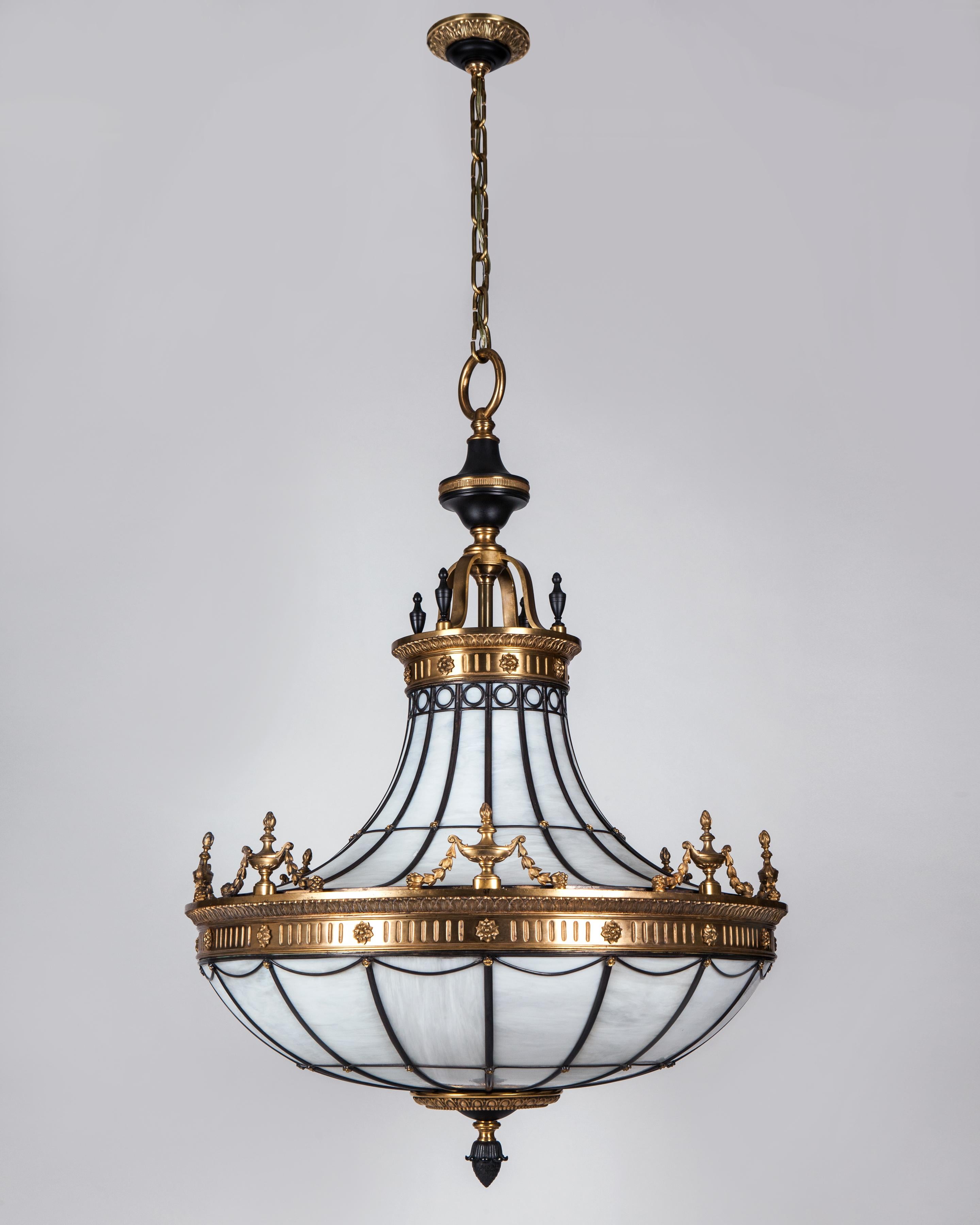 AHL3554

A large antique leaded glass chandelier with bronze framing in a combination of dark and bright-burnished finishes. The metalwork is detailed with twin friezes of leaf-and-dart moldings over rosettes and fluting. Each molding topped with