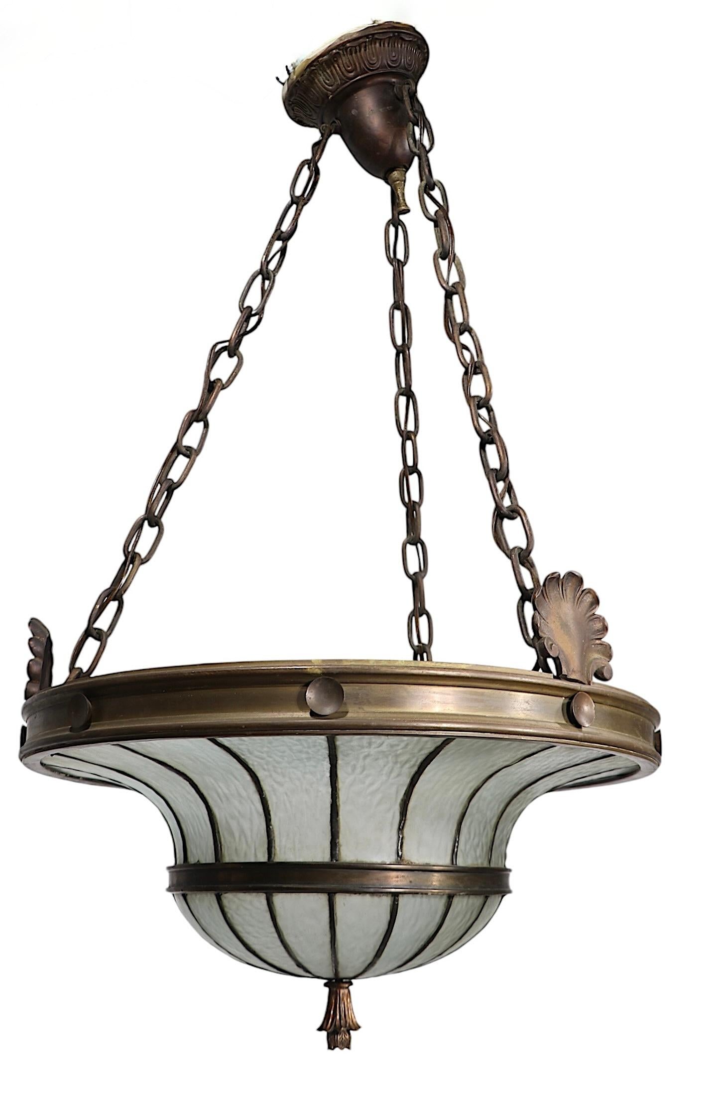 Exceptional brass/bronze and textured pebbled glass leaded chandelier, in very good, clean, original and working condition. The fixture features a brass, or bronze circular frame with three decorative cast brass shell form elements, with an inverted