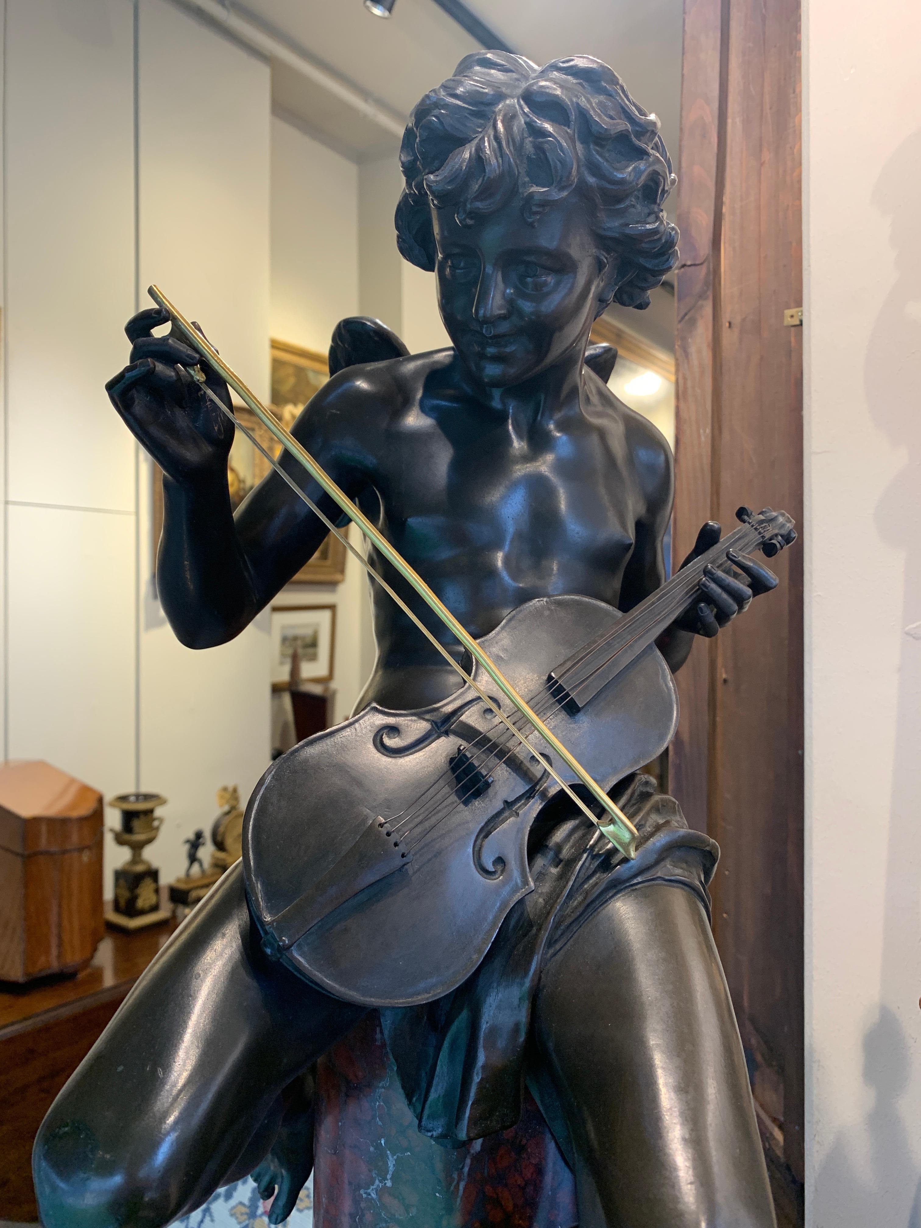 Bronze sculpture of an angel is playing a violin with gilt detail. The shaped rouge marble base is decorated with two bronze doves and gilt,
circa 1870.