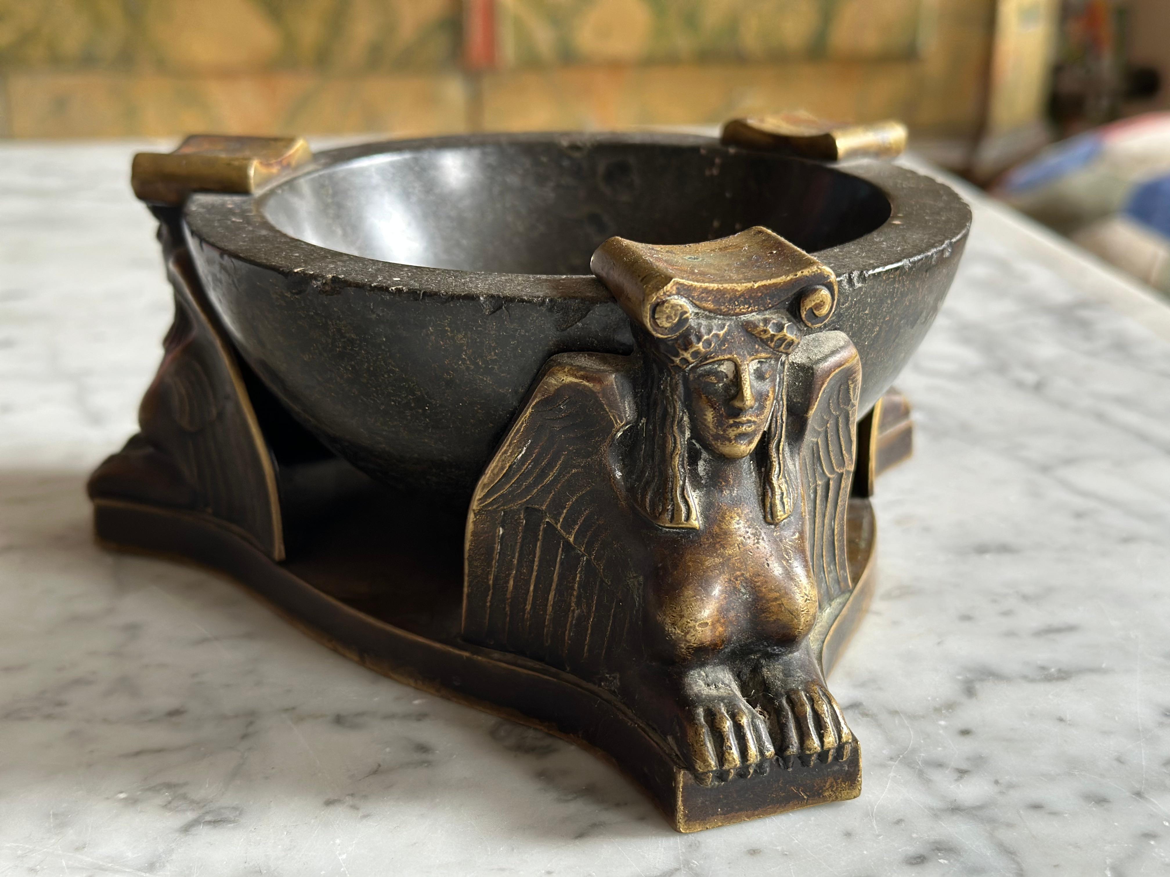 This monumental ashtray, attributed to the German designer and architect Albin Müller (1871–1941), embodies the refined aesthetics of the Vienna Secession. Crafted in the early 20th century, the piece unites a heavy serpentine stone base with a
