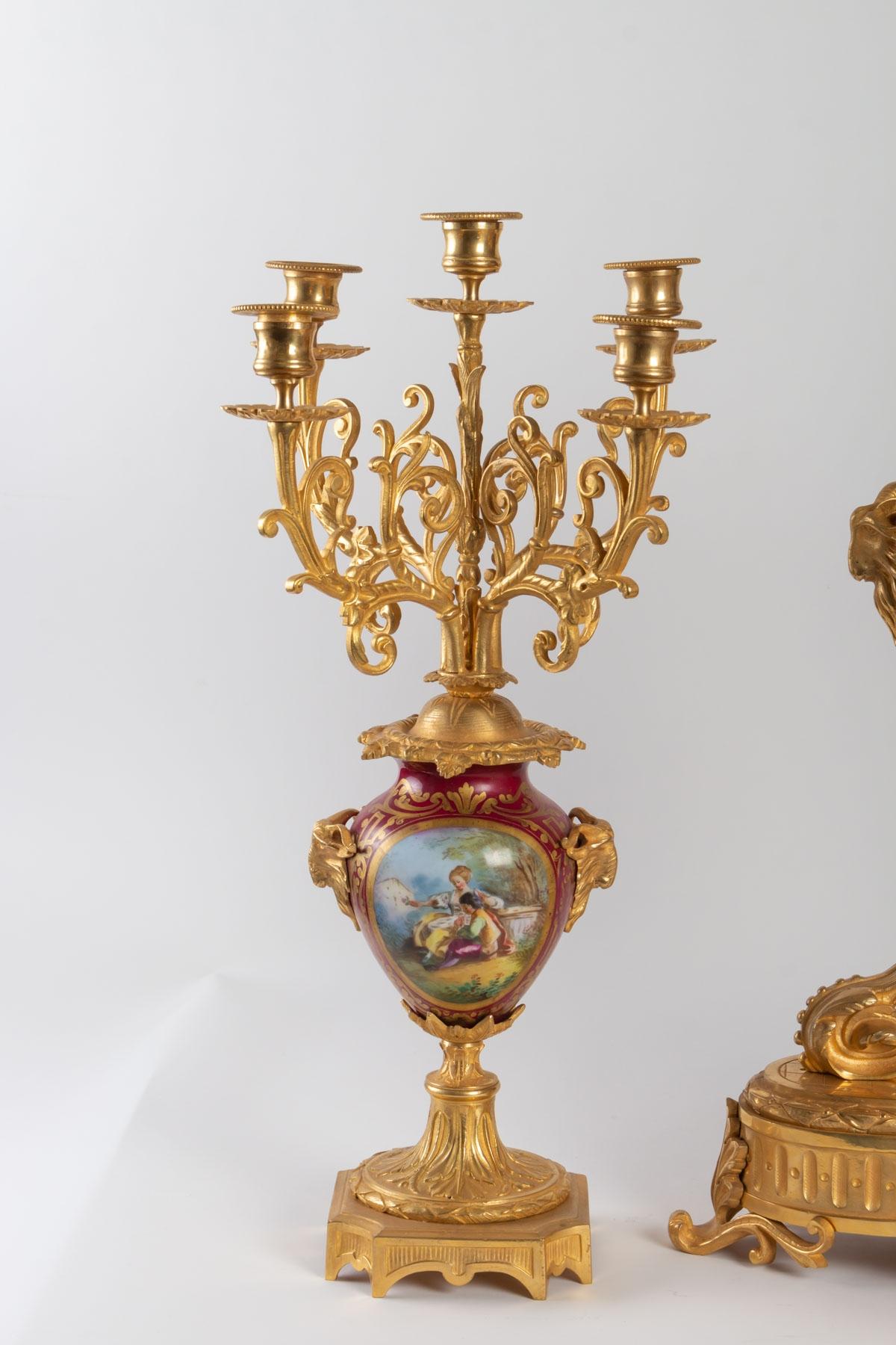 Louis XVI style mantel set in bronze and Sèvres Porcelain, comprising a large clock decorated with two doves, Roman numerals framed by a cherub, two ram's heads on the sides, rich foliated decoration on the base.
Late 19th century period, Napoleon