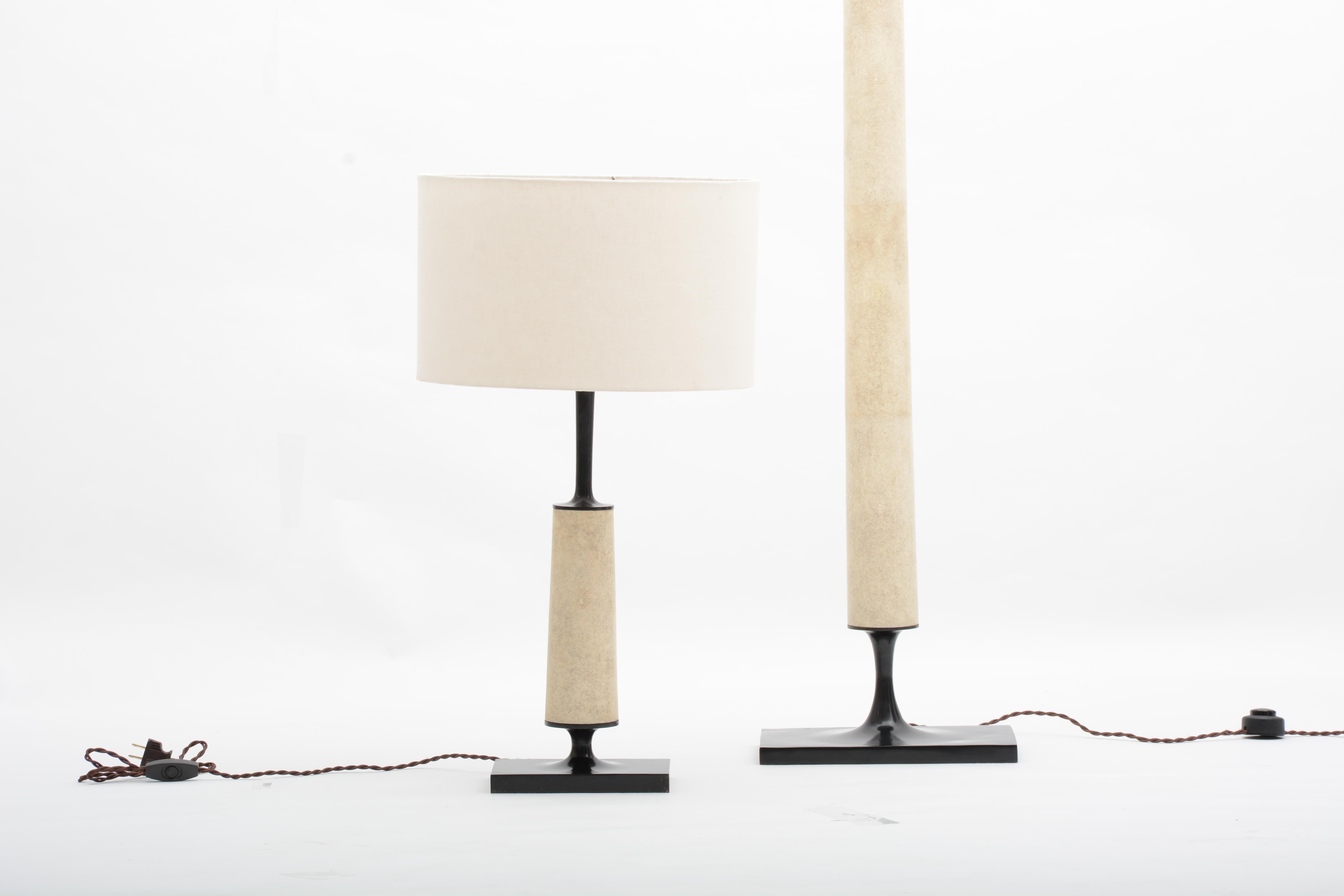 The Jaya table lamp is comprised of a cast bronze base, wrapped in natural shagreen. A classically modern lamp clad in noble materials. 

Cast bronze lamp with shagreen stem and linen shade produced using the superior lost wax bronze casting