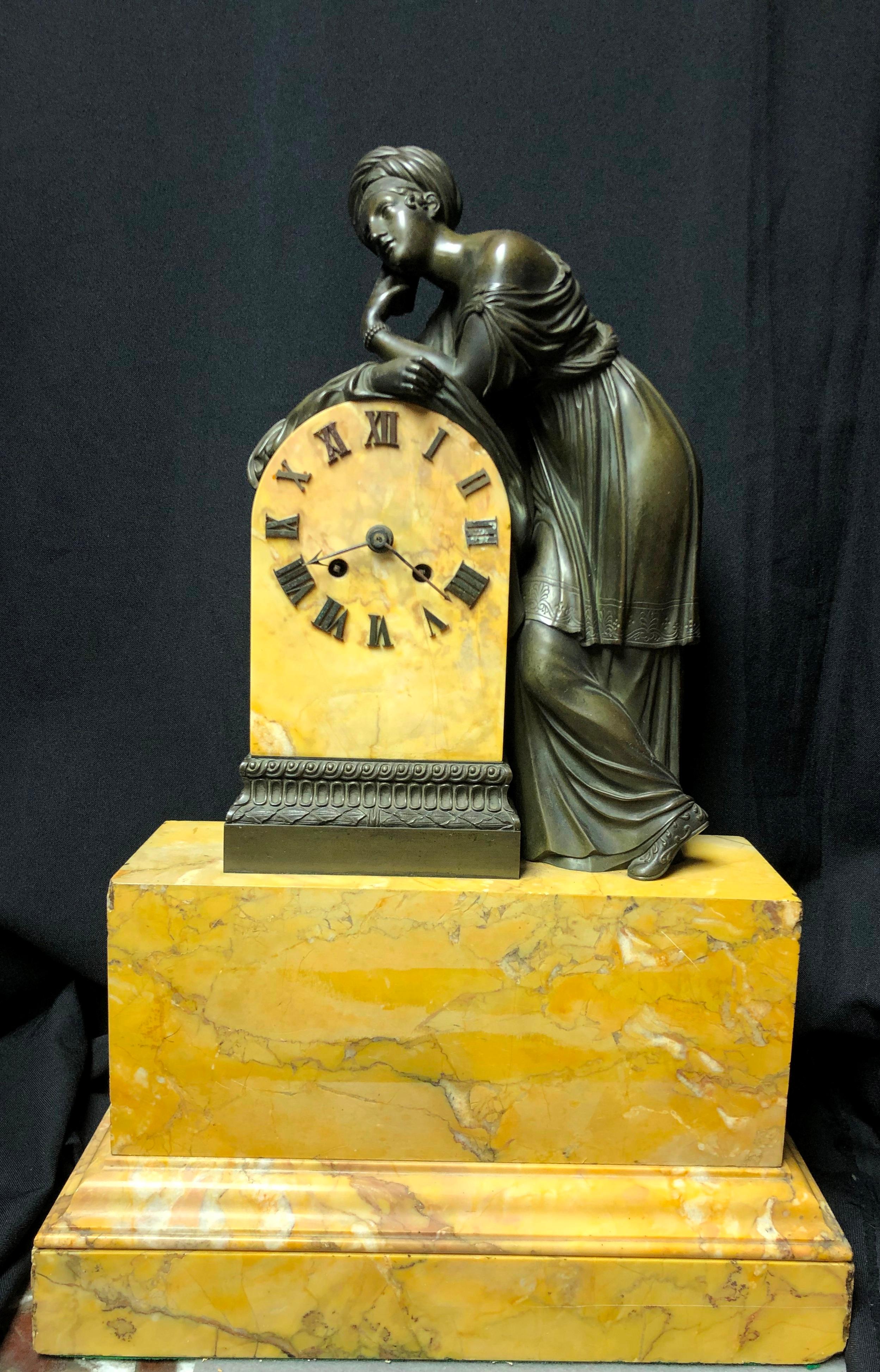 Lovely French Charles X patinated and sienna marble mantel clock.
A beautiful Neoclassical patinated bronze standing woman leaning on the clock, standing on Sienna marble plinth. 
The clock mechanism is not guaranteed.  