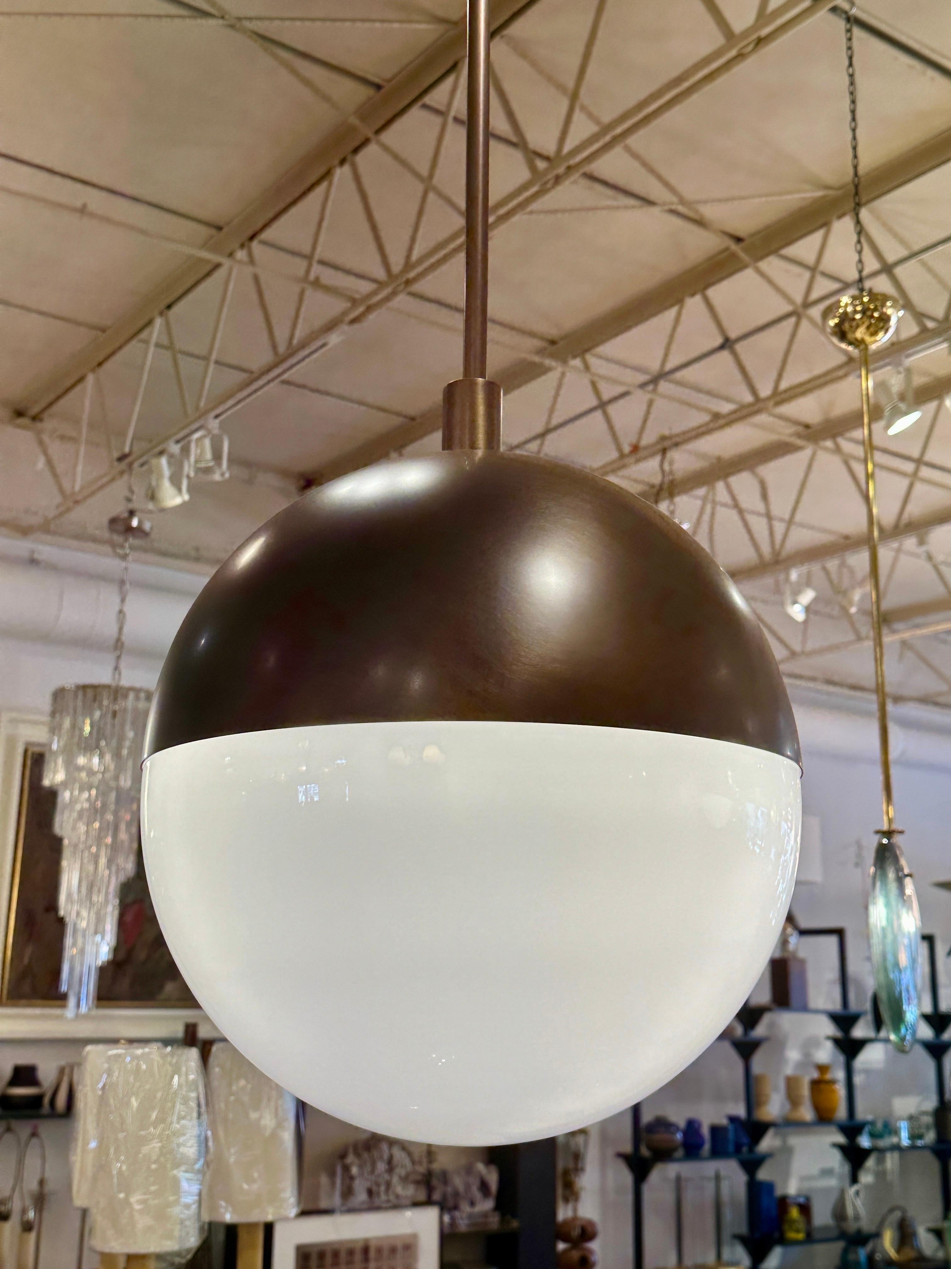 Cette magnifique suspension italienne en bronze et verre blanc en forme de globe est si classique avec son demi-dôme en finition bronze satiné et le dôme inférieur en verre blanc de Murano.  Une seule ampoule à l'intérieur fournit beaucoup de