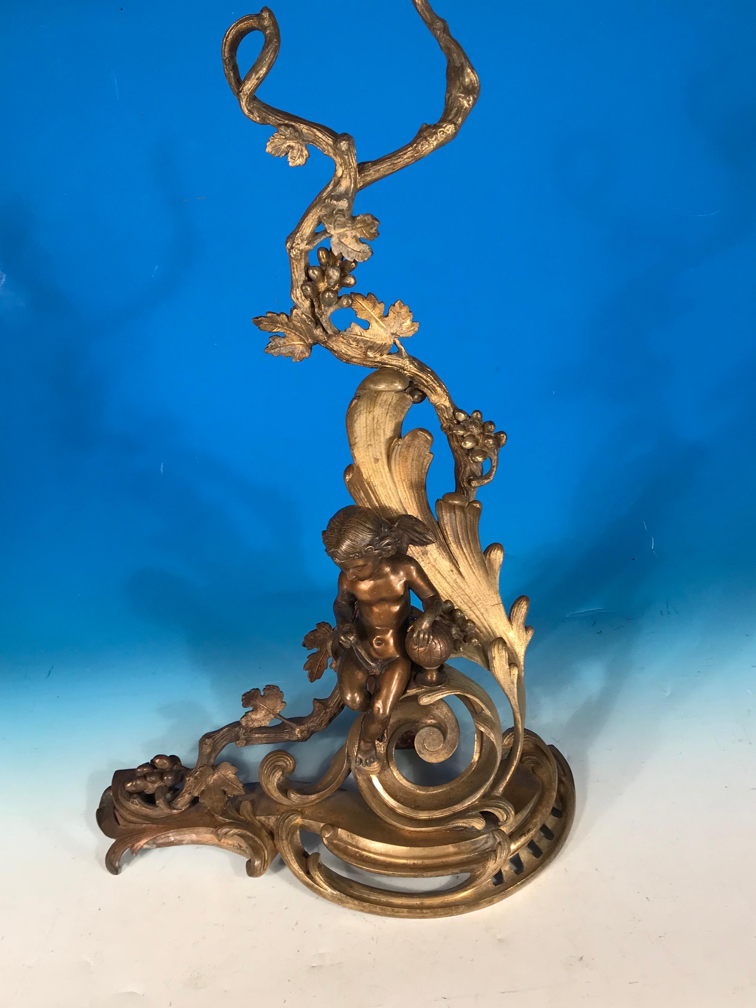 Very decorative Rococo style bronze andirons. Dating back to the 19th century, the pair of andirons comes from France. They are embellished with two putti and curved rocaille and oak branches. The figurines represent the allegory of science and