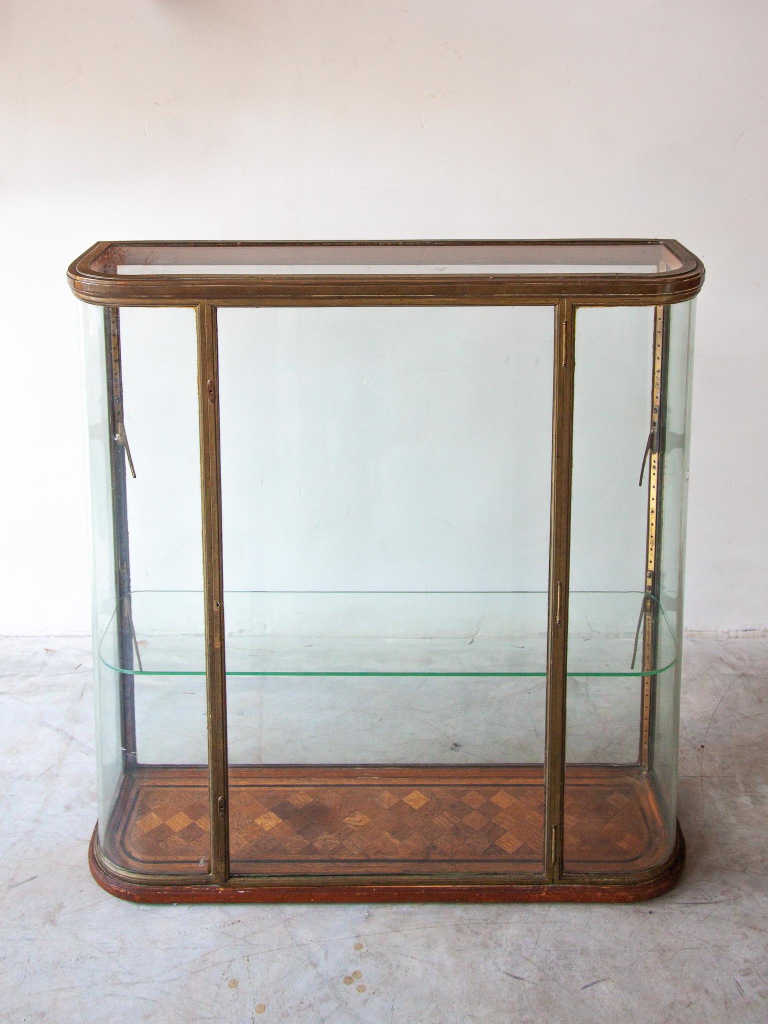 Beautiful bronze antique table display vitrine in glass with curved glass panels framed in bronze. This display showcase was once a part of a weapon-shop standing on the counter for the presentation of small model weapons in the 19th century. Once