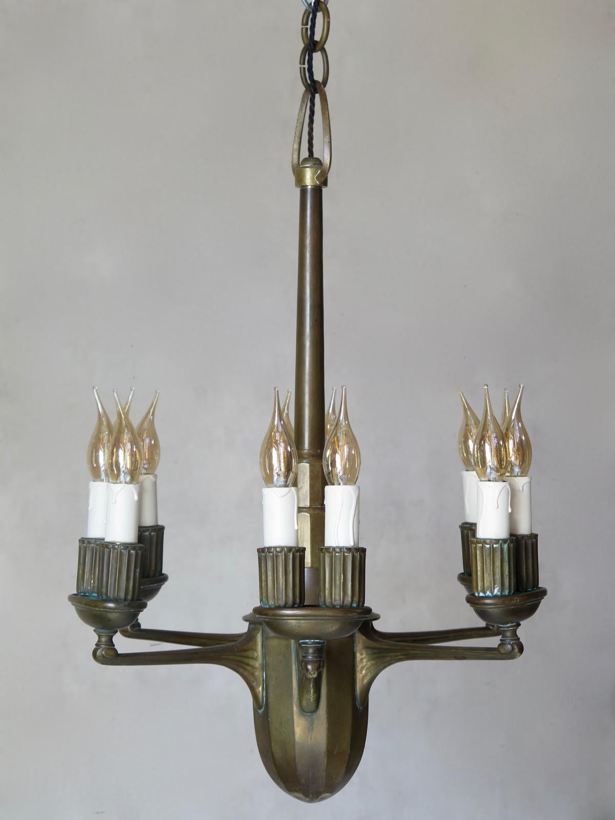 Elegant and heavy six-arm and twelve-light solid bronze chandelier with lovely lines, drawing on both Art Nouveau and Art Deco influences. Each arm supports an ovoid cup with two ridged light holders. Stepped stem. Ovoid stem base. Newly rewired.