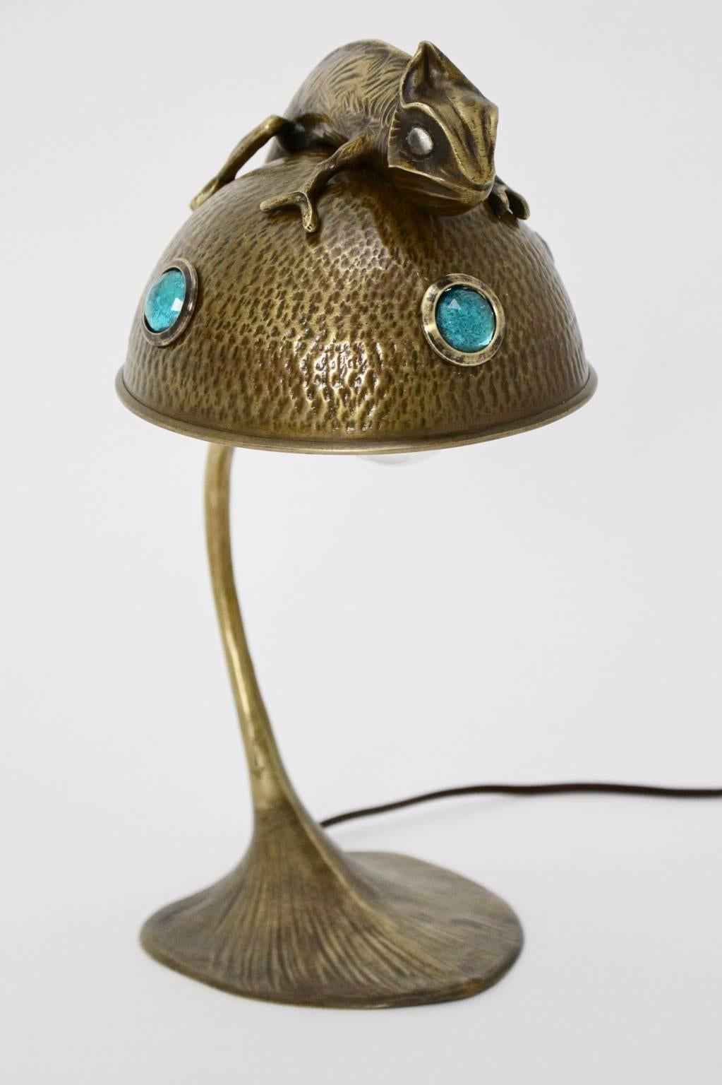 Lovely bronze table lamp Art Nouveau, France.
A Chamaeleon with colorless glass eyes is sitting on the dome shade. The stem of the table lamp looks like a plant stem.
The table lamp shade is further decorated with three green glass eyes and shows