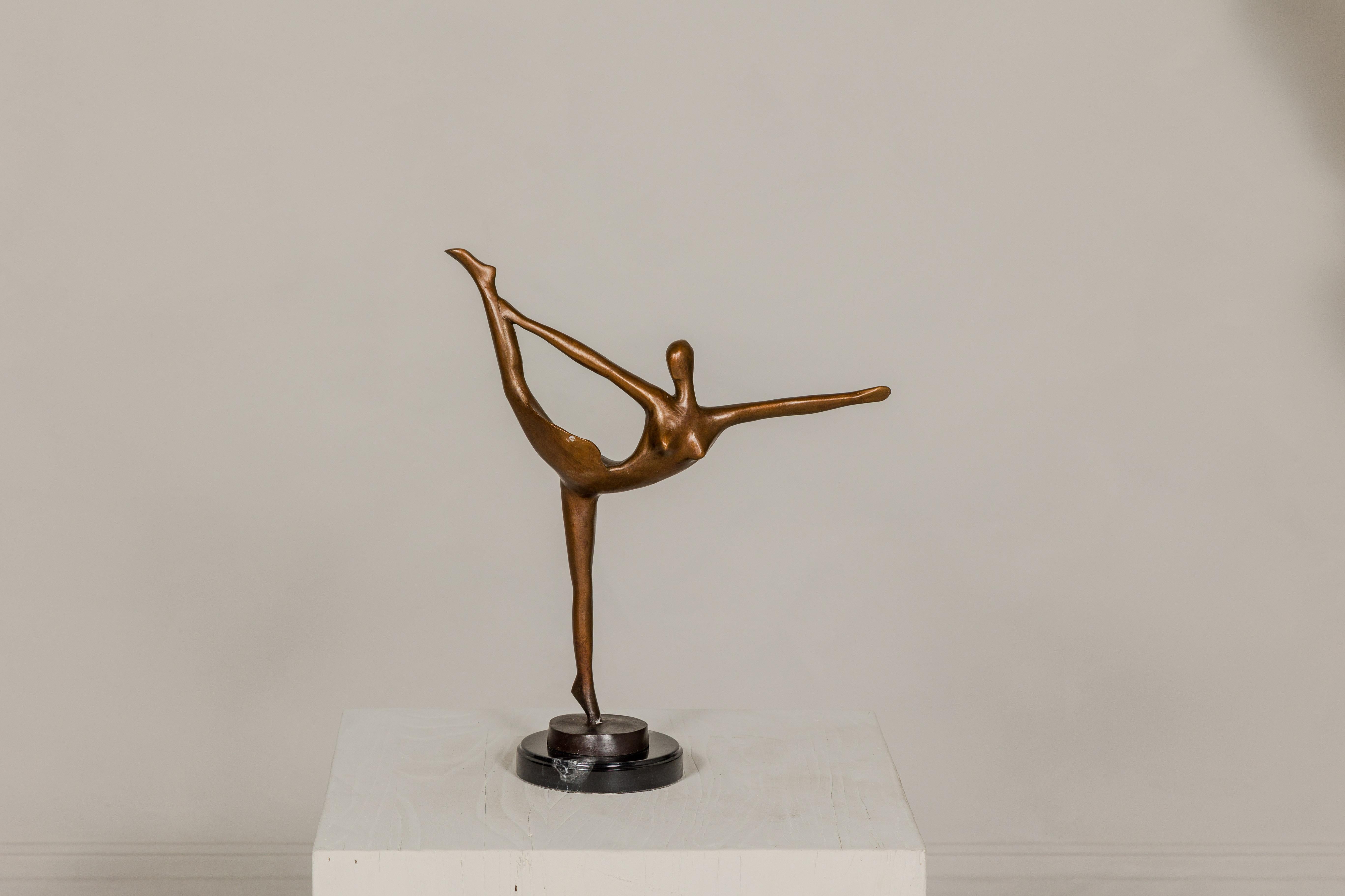A bronze ballerina statuette on circular black marble base with white veining. Enhance your home's décor with the captivating grace of this exquisite bronze ballerina statuette, poised on a circular black marble base with white veining. Its elegant