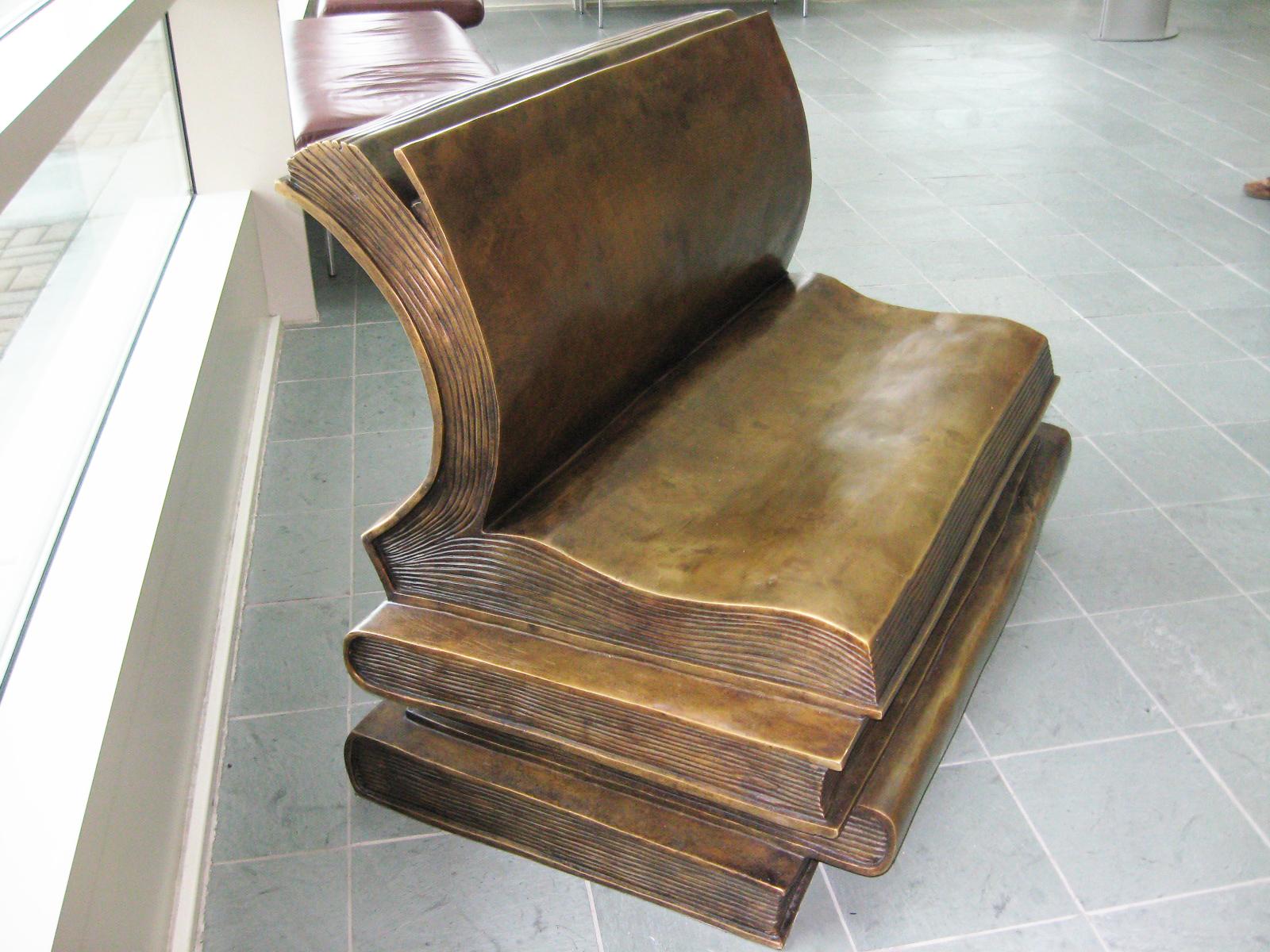 This beautifully designed limited edition lost-wax bronze book bench features four books stacked upon each other with the top book open midway. The cover of the top book artistically curves backward to act as the back rest for the bench, while the