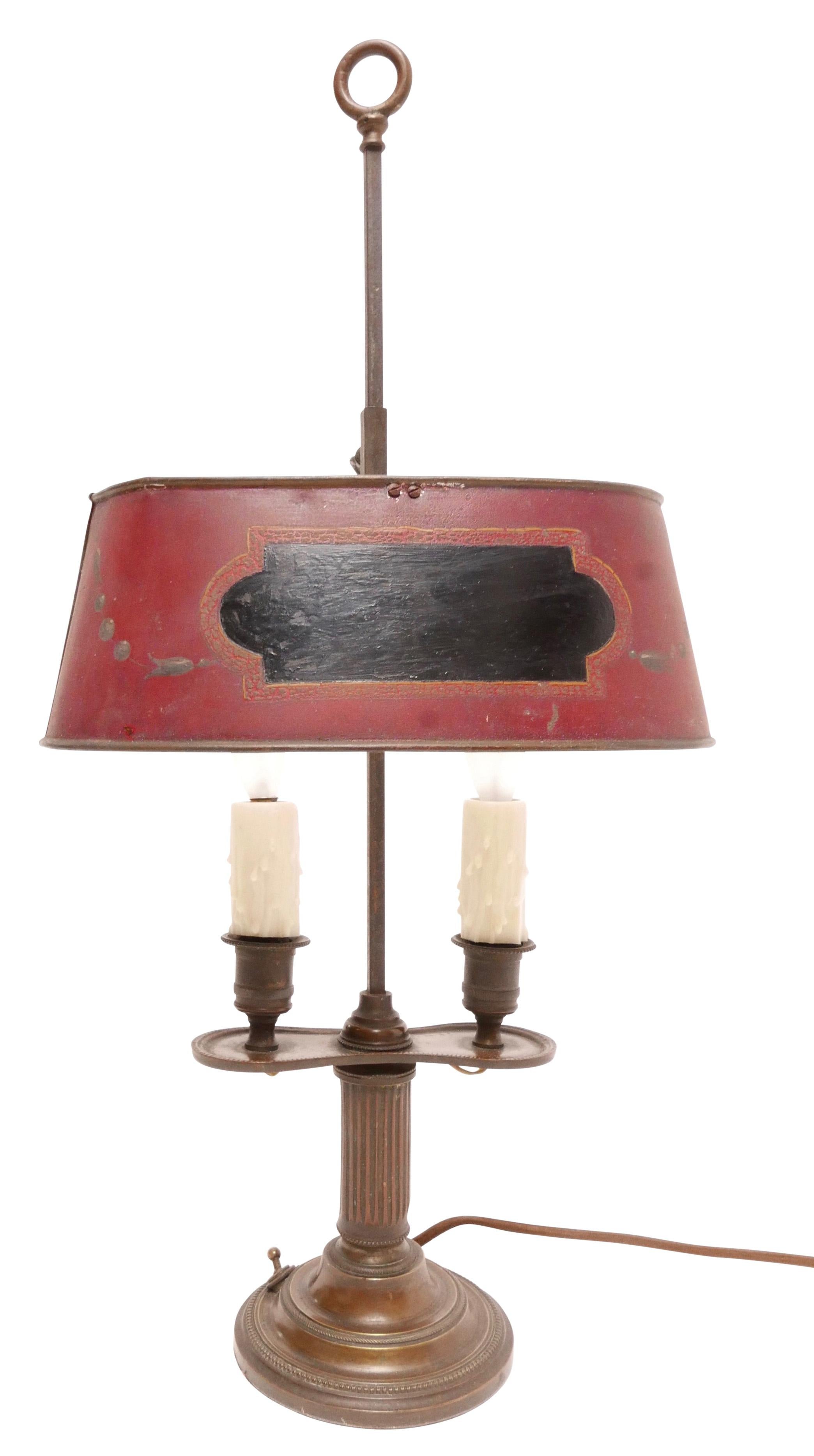 Lampe bouillotte à deux lumières en bronze avec patine d'origine et abat-jour peint en tole rouge avec des accents noirs et verts. La peinture extérieure de l'abat-jour est d'origine, l'intérieur de l'abat-jour a été rafraîchi il y a quelque