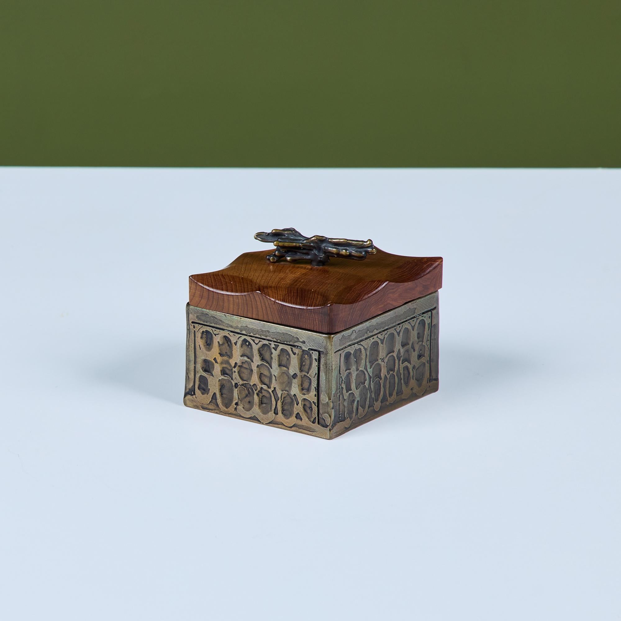 Caja decorativa con tapa de Chris y Pat Shatsby c.1990, EE.UU. La caja en forma de diamante está hecha de bronce texturizado con una tapa de madera tallada a mano. La tapa está rematada con una escultural asa de bronce. Firmado 