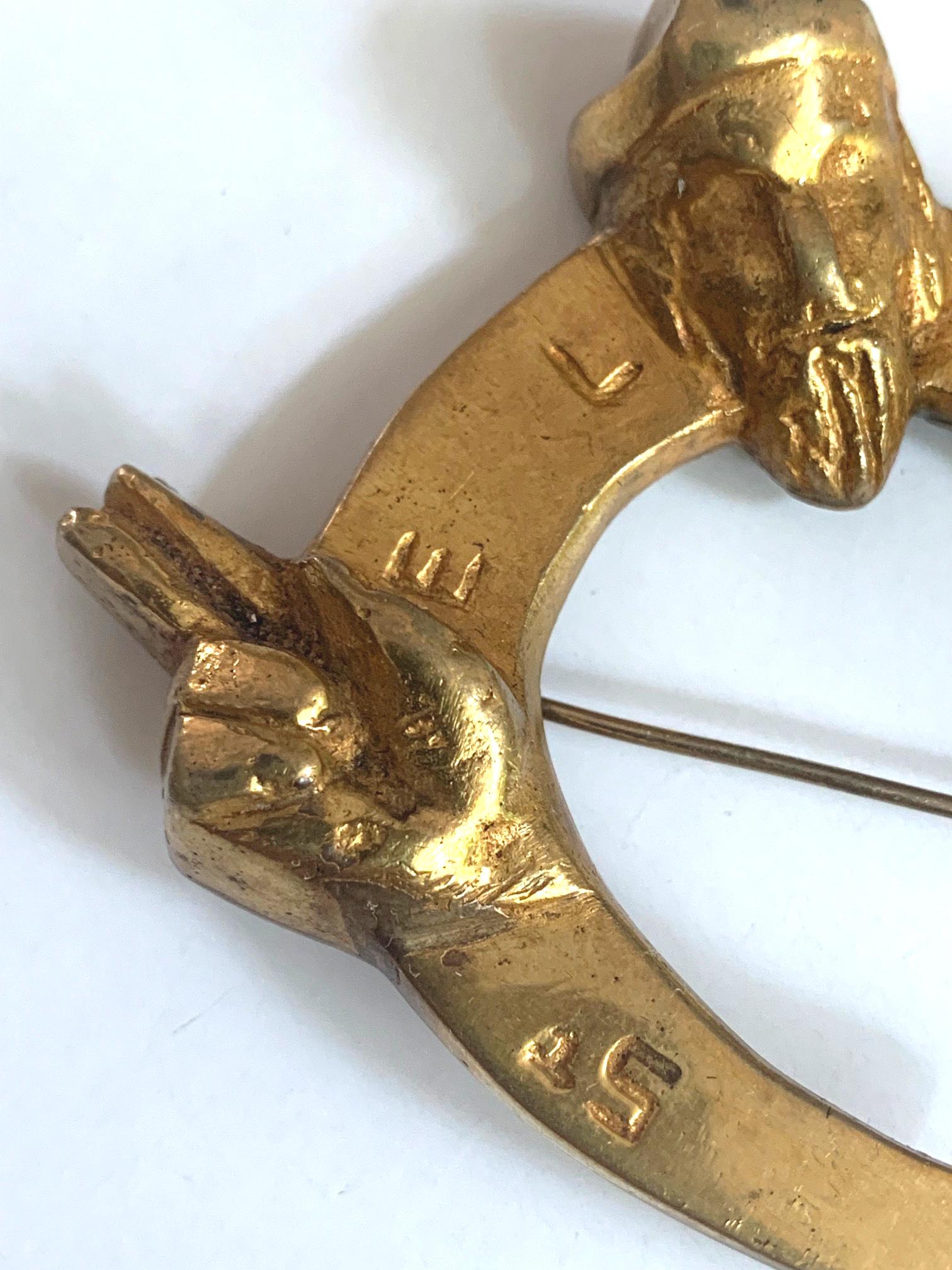 A rare bronze brooch St Eloi by Parisian art jeweler Line Vautrin ((French, 1913–1997) circa 1946. Brilliantly designed in the shape of horseshoe with the saint spreading his arms holding the attribute. With St Eloi carved in the front. Marked on
