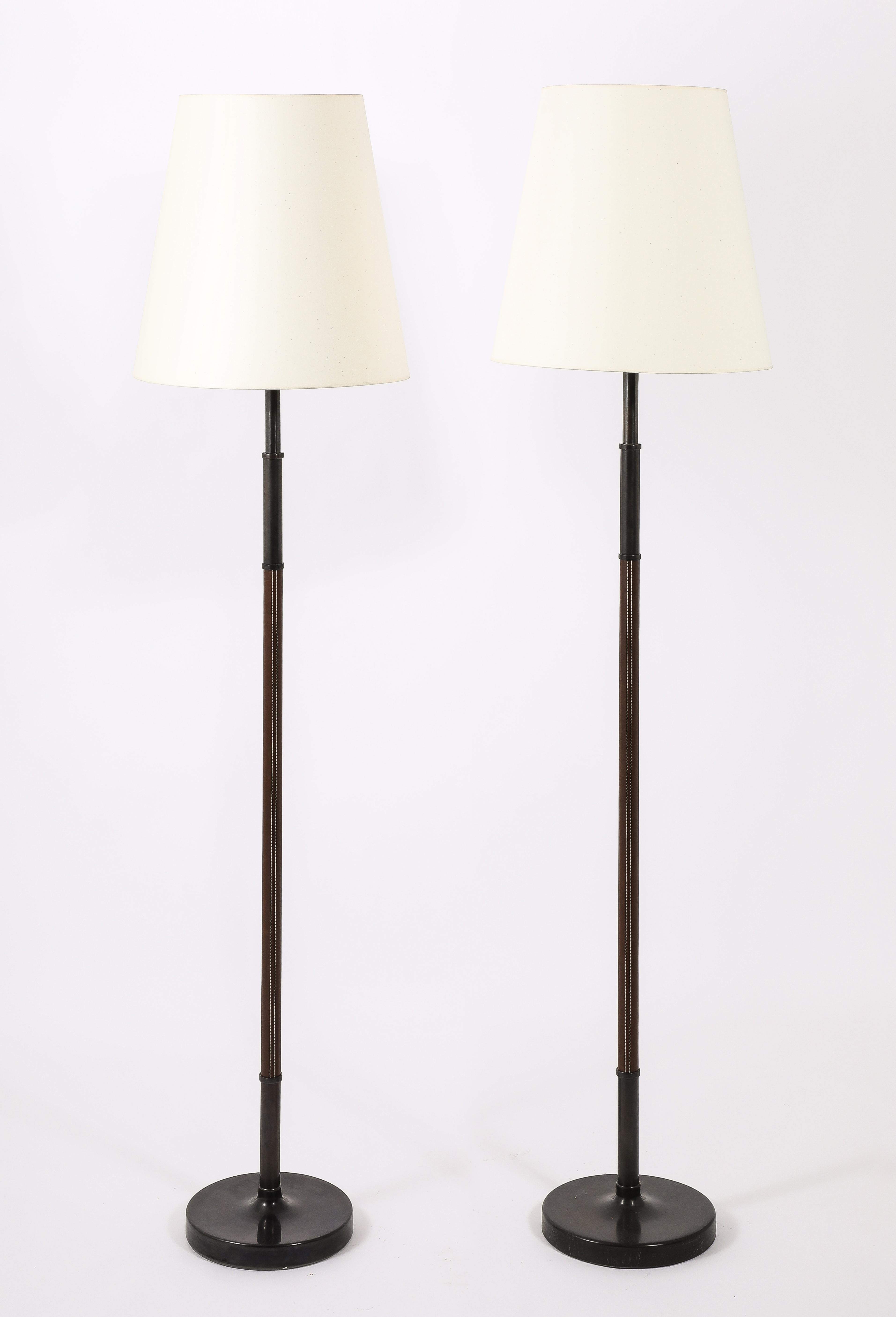 A pair of floor lamps by MetalArte Wrapped in a Chocolate leather, on heavy bronze bases. Signed on the counterweight.
