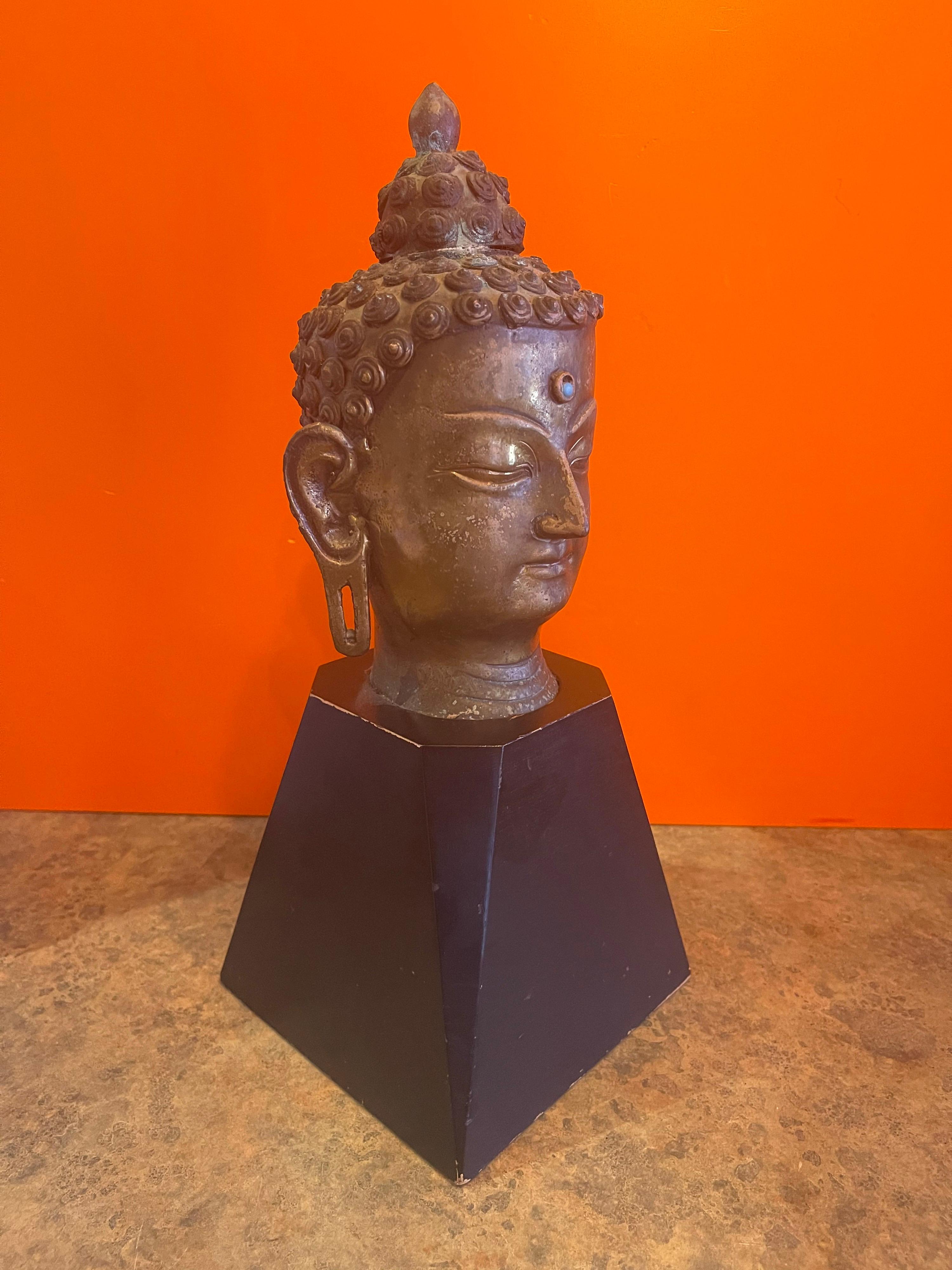 Decorative bronze Buddha headon black wood base, circa 1970s. The piece is in very good vintage condition and measures: 6
