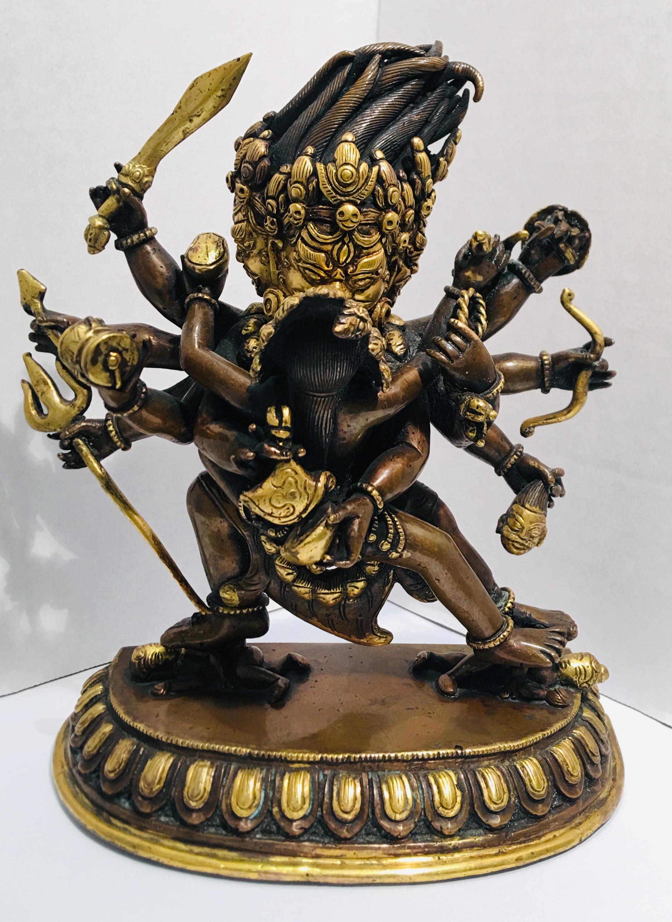 A Sino-Tibetan bronze Yamantaka (Sanskrit: Vajrabhairav) with 3 buffalo-head faces and Medusa-like dreadlocks, and 10 arms, holding weapons and objects in every hand as he furiously embraces his consort, Vajravetali, who wears the 5 pointed crown,