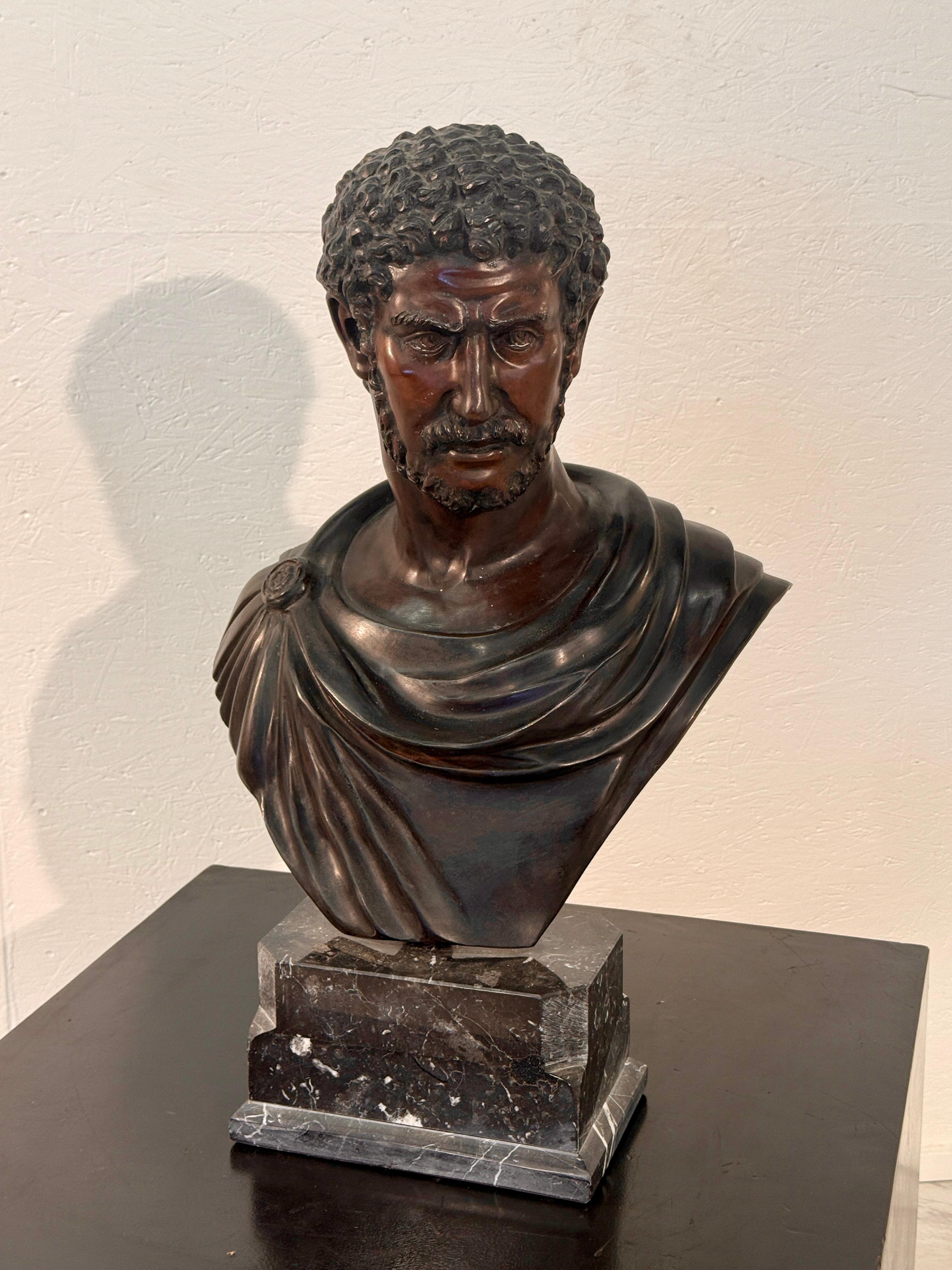 A finely crafted bronze bust depicting the Roman Emperor Caracalla, renowned for his commanding presence and fierce expression. The sculpture captures his strong features with remarkable detail, including tightly curled hair, a stern gaze, and a