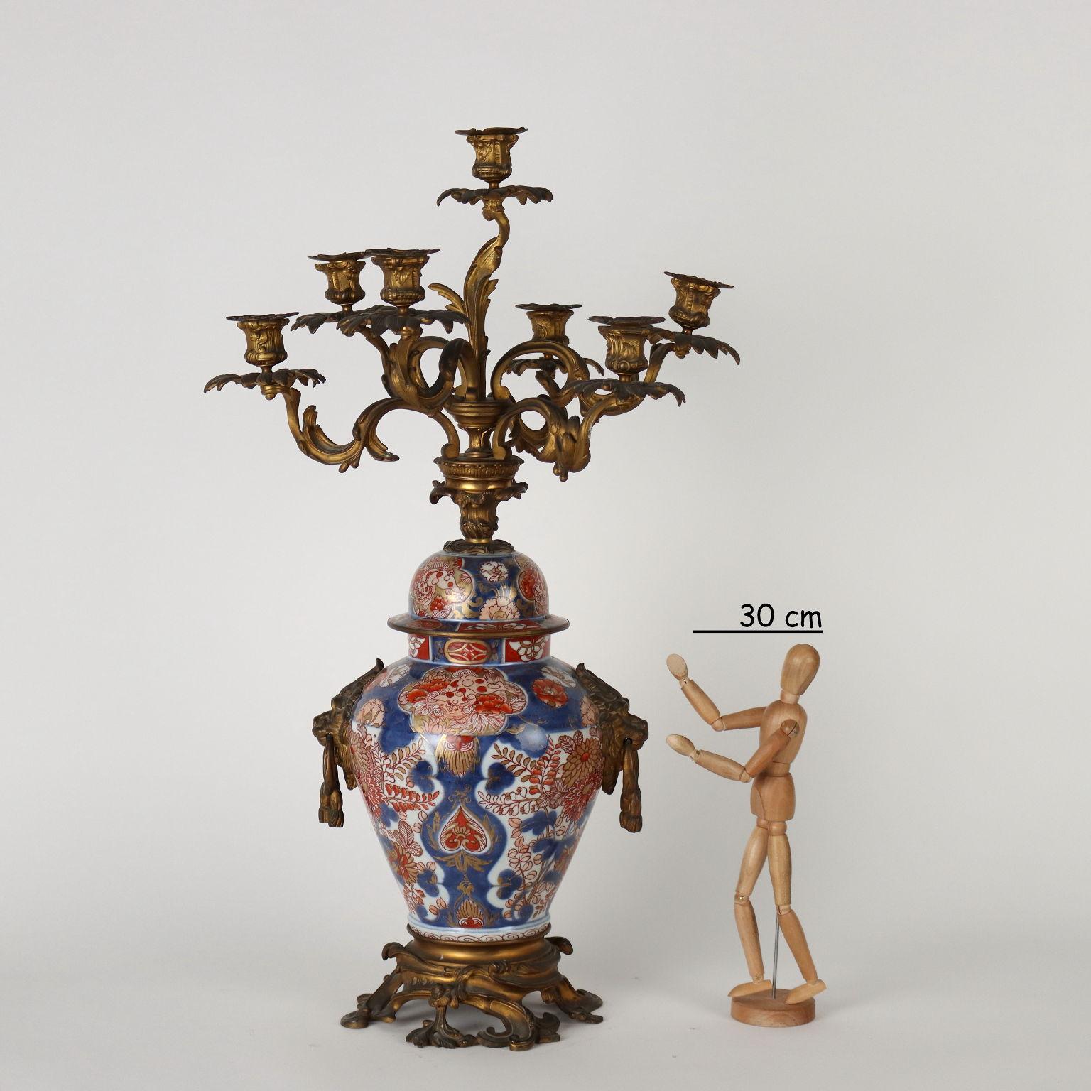 Imari porcelain vase with gilt bronze mounts with candlestick function. The vase painted in blue below has polychrome enamel decorations of plants, flowers and Shishi lions within reserves. Base in gilded bronze with rocaille and lion handles on the