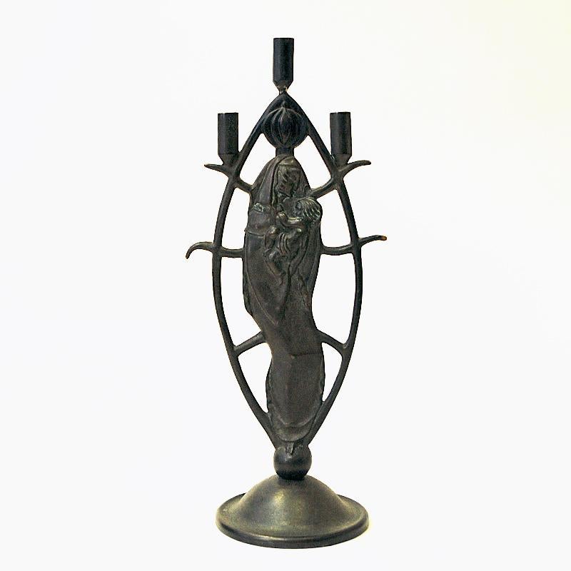 Lovely and heavy ovalshaped bronze candle holder for three thinner candles by Oscar Antonsson for Ystad Metall - Sweden 1930s. Nicely sculpted body and a decor in the middle of a mom with a child in her arms. The candle holder are nice both with and