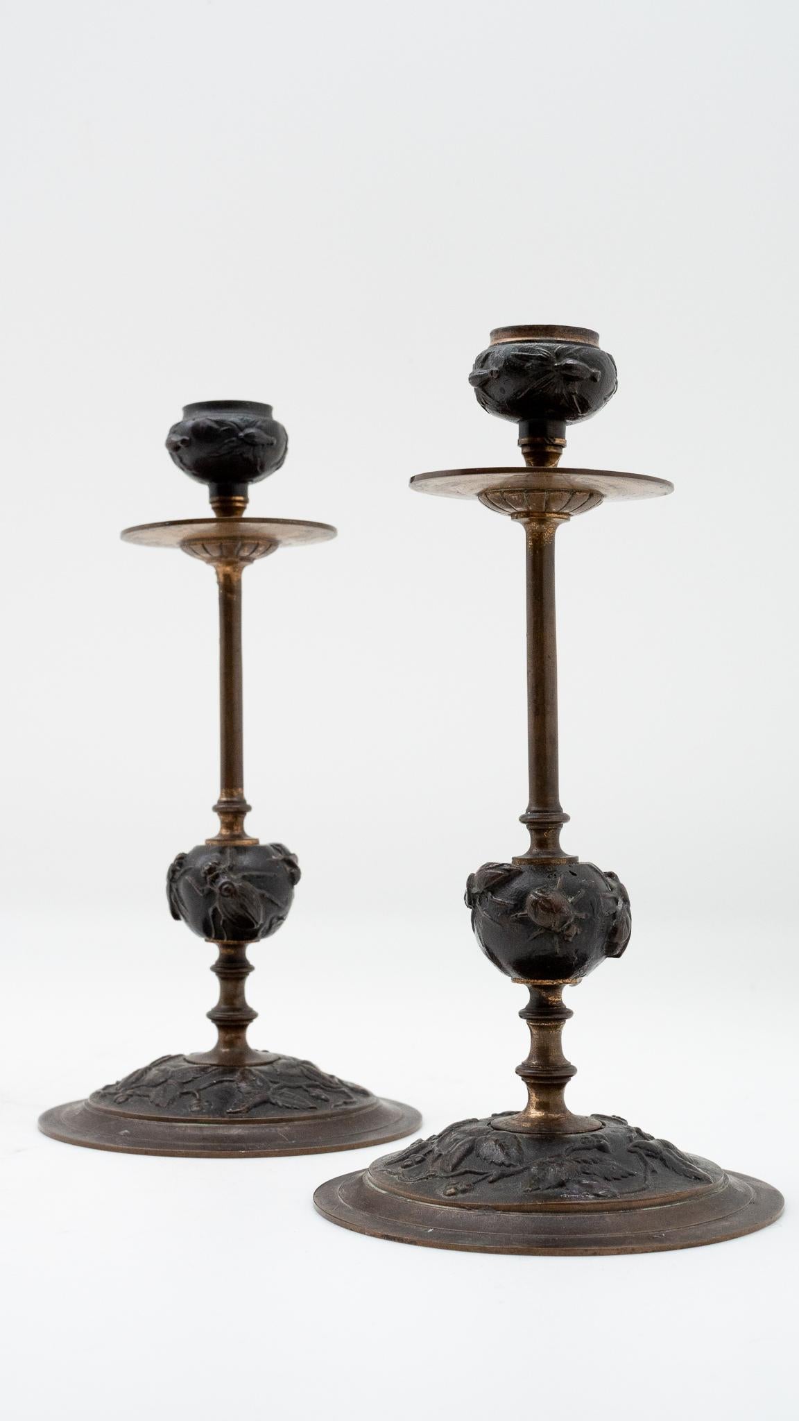 Pair of 19th century French bronze candlesticks with insect, berry vine, and leaf decorations.