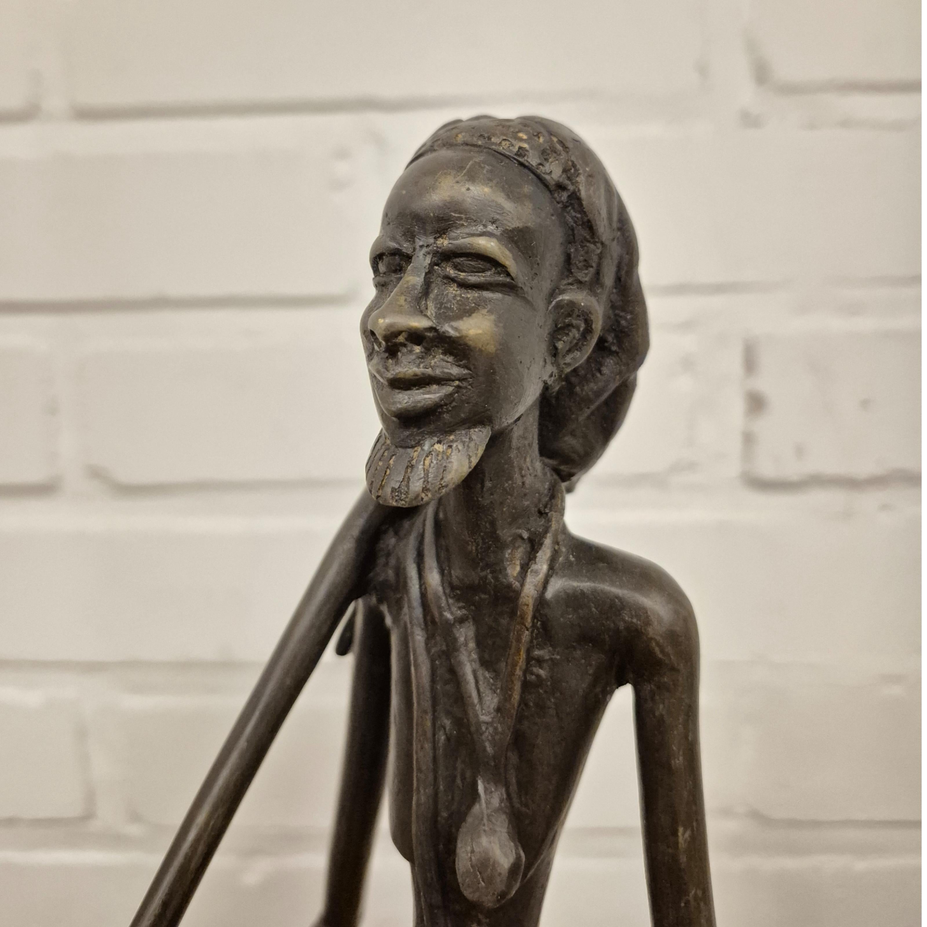 Statue en bronze coulé d'un chasseur tribal africain. Il a un aspect surréaliste en raison de l'exagération des traits du visage et de l'allongement des membres et du corps. 
Probablement fabriqué dans la région de Tanzanie dans les années 1960.

Le