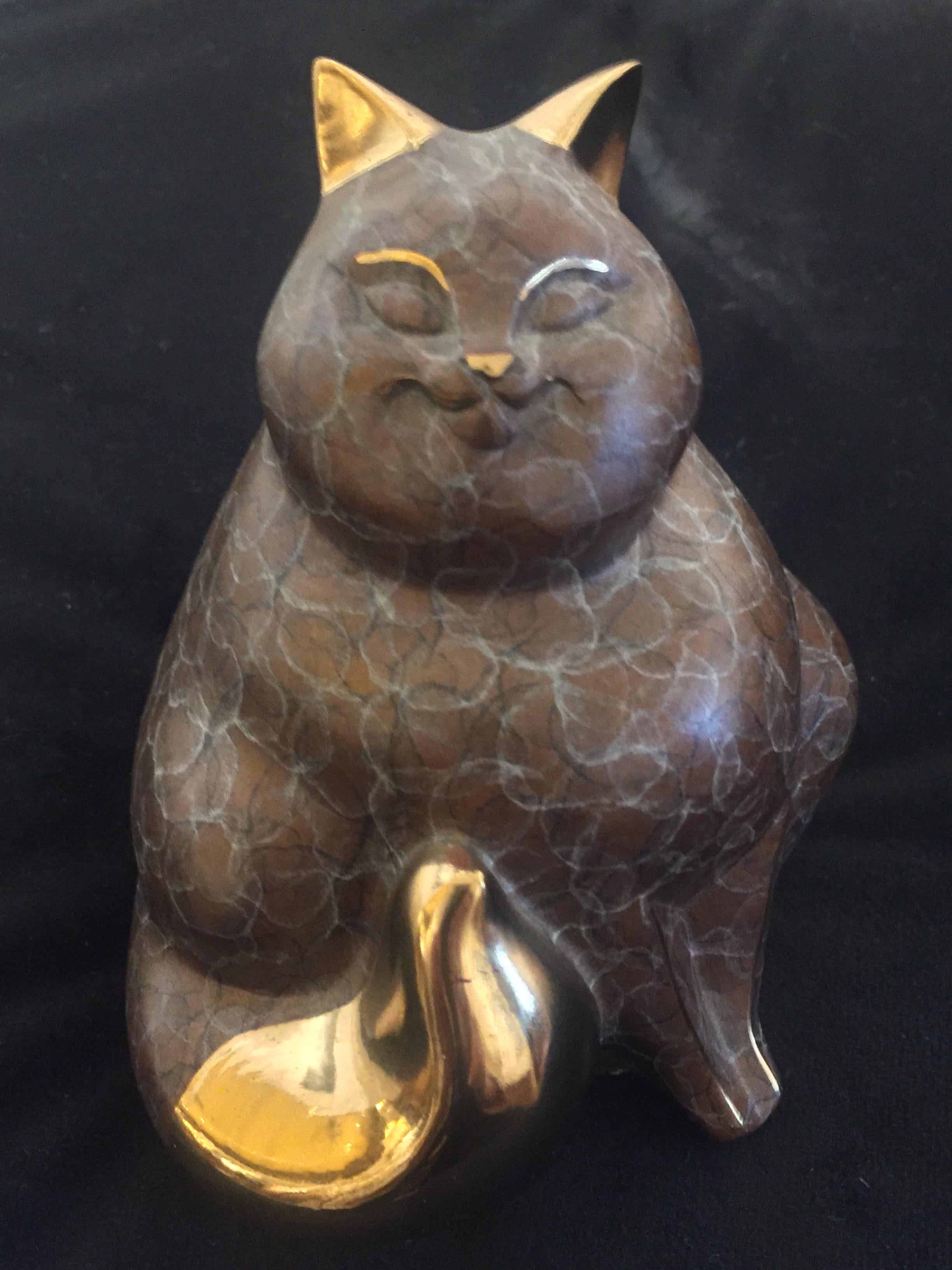 Small bronze cat sculpture with reddish brown details, accented by gold and silver highlights on eyes, ears, front legs, and tail. Marks on low back 