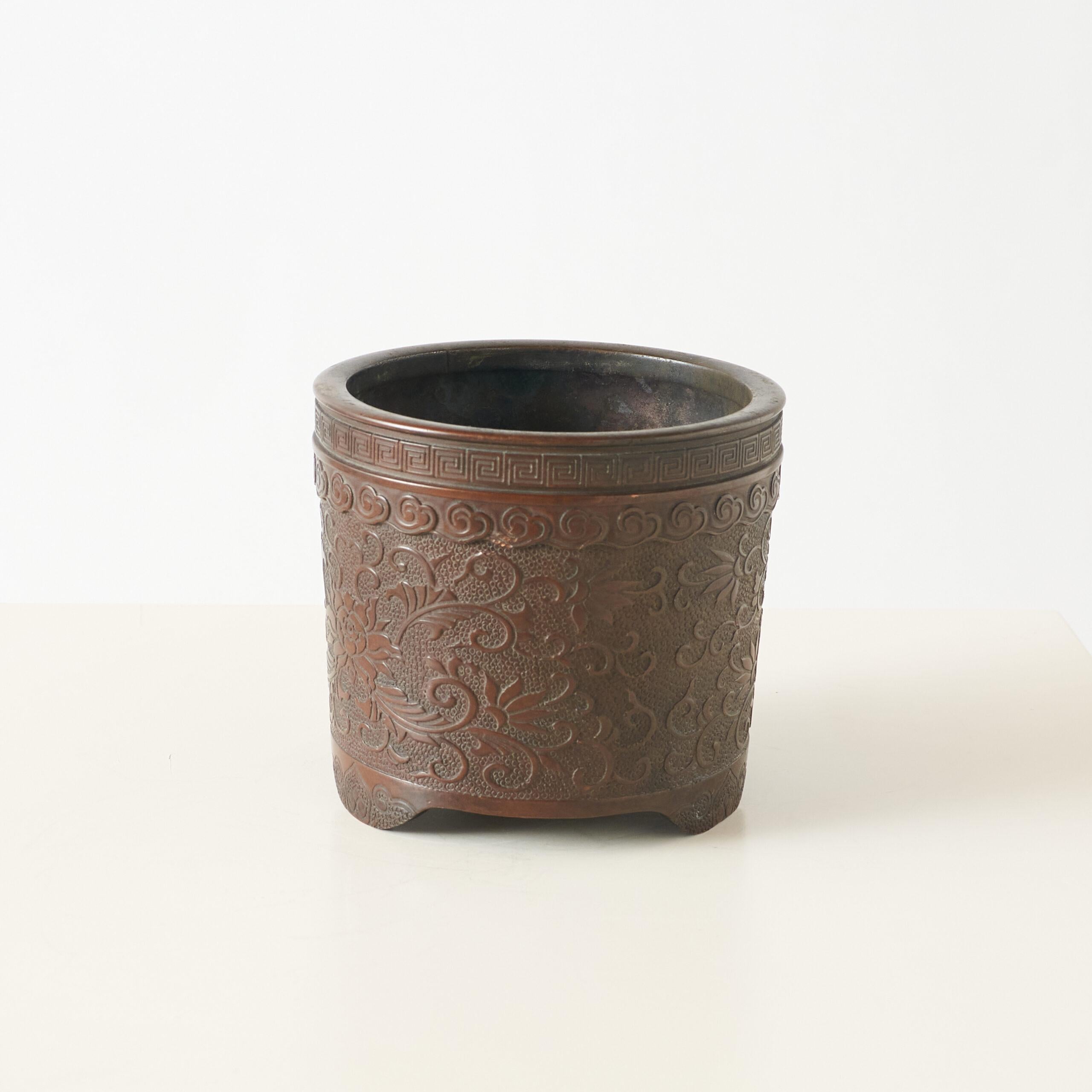 Incensiere in bronzo con intagli di loto

Incensiere decorativo in bronzo con intricati intagli a forma di loto e un motivo geometrico a meandro intorno al bordo. Il recipiente presenta densi motivi floreali, forse loto o peonia, in rilievo. Con il