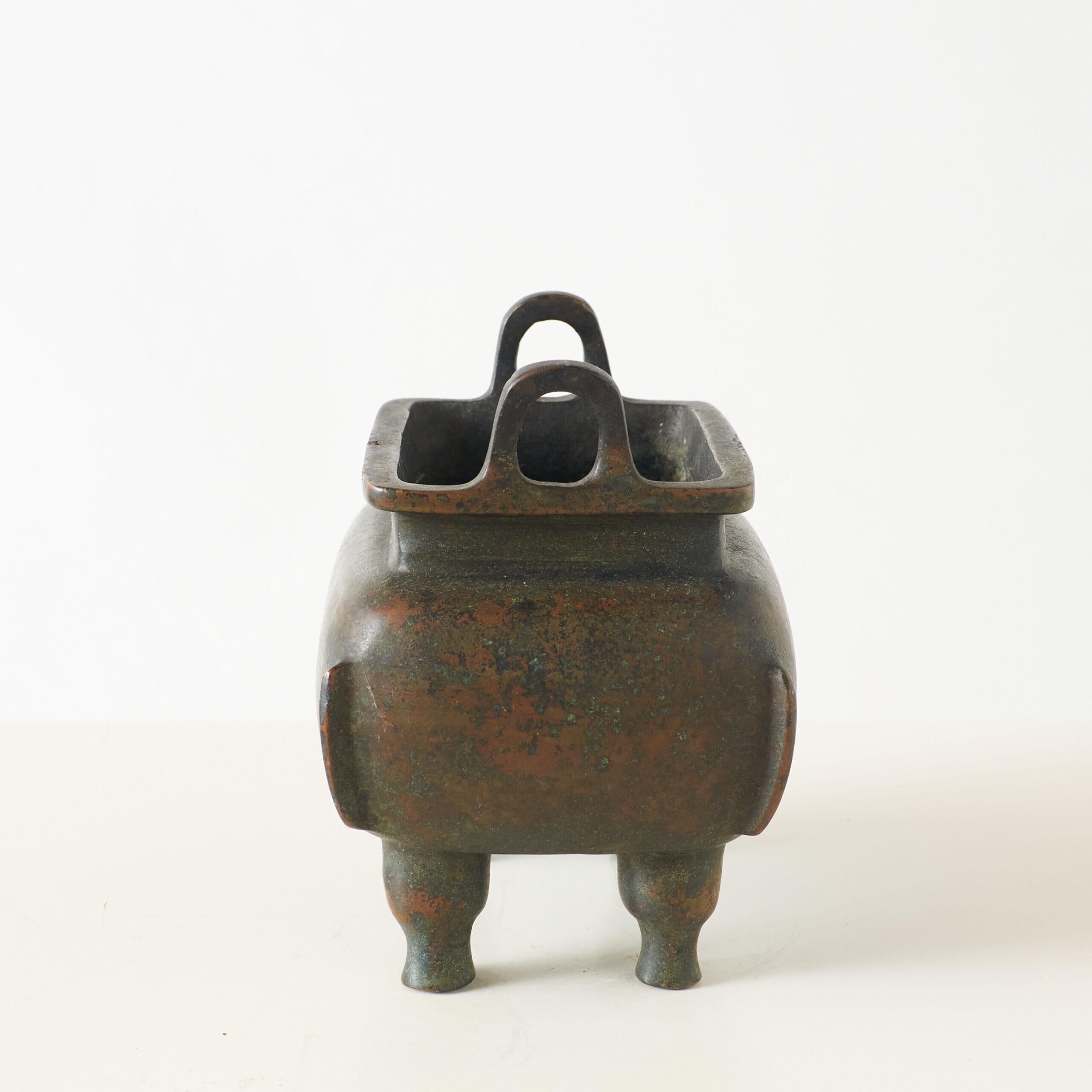 Chinese Bronze Censer with Two Handles

This Chinese bronze censer features a rectangular shape with rounded sides, double ears, and a rich, dark patina. The base is marked with the reign mark “大明宣德” (Dà Míng Xuāndé), indicating the Xuande period