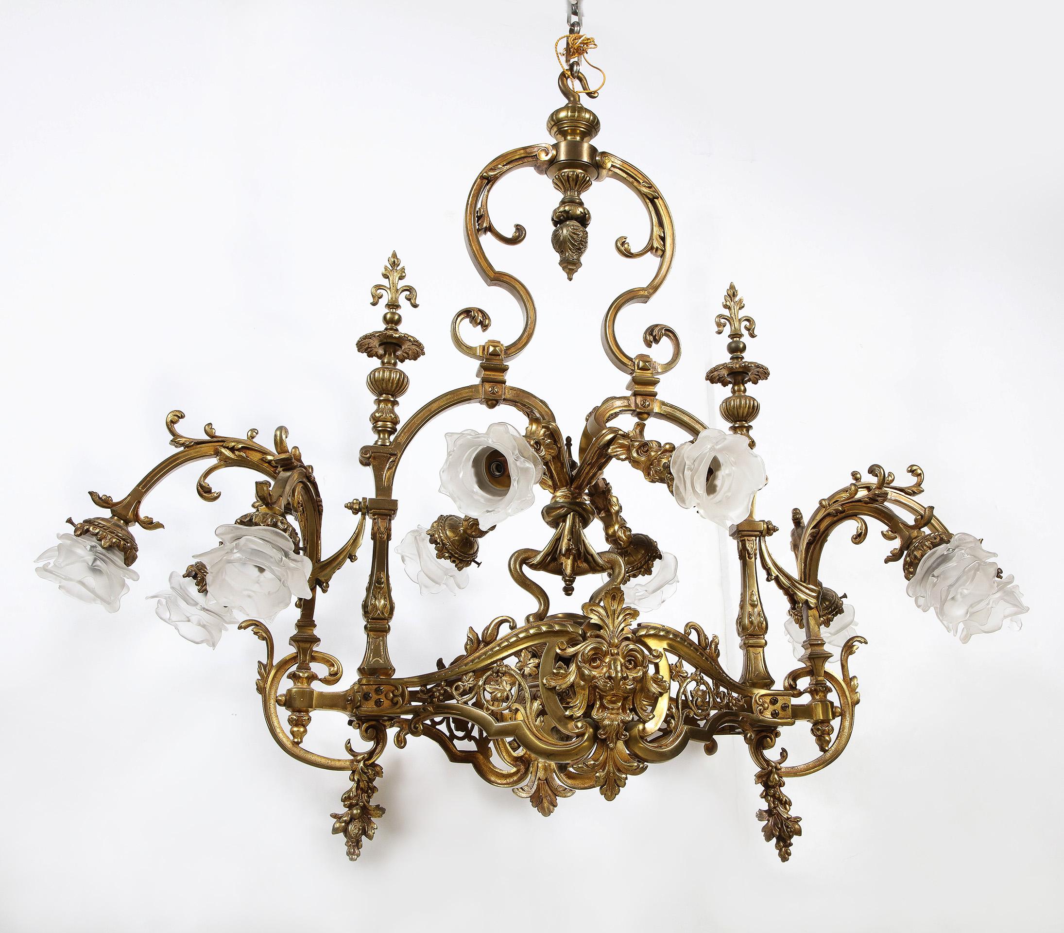 A very fine French Belle Epoque 19th century Louis XIV style ten-light gilt-bronze chandelier. The ovoid shaped body with scrolling arms ending in floral frosted glass shades, the whole over a pierced basket centered by a gothic face.