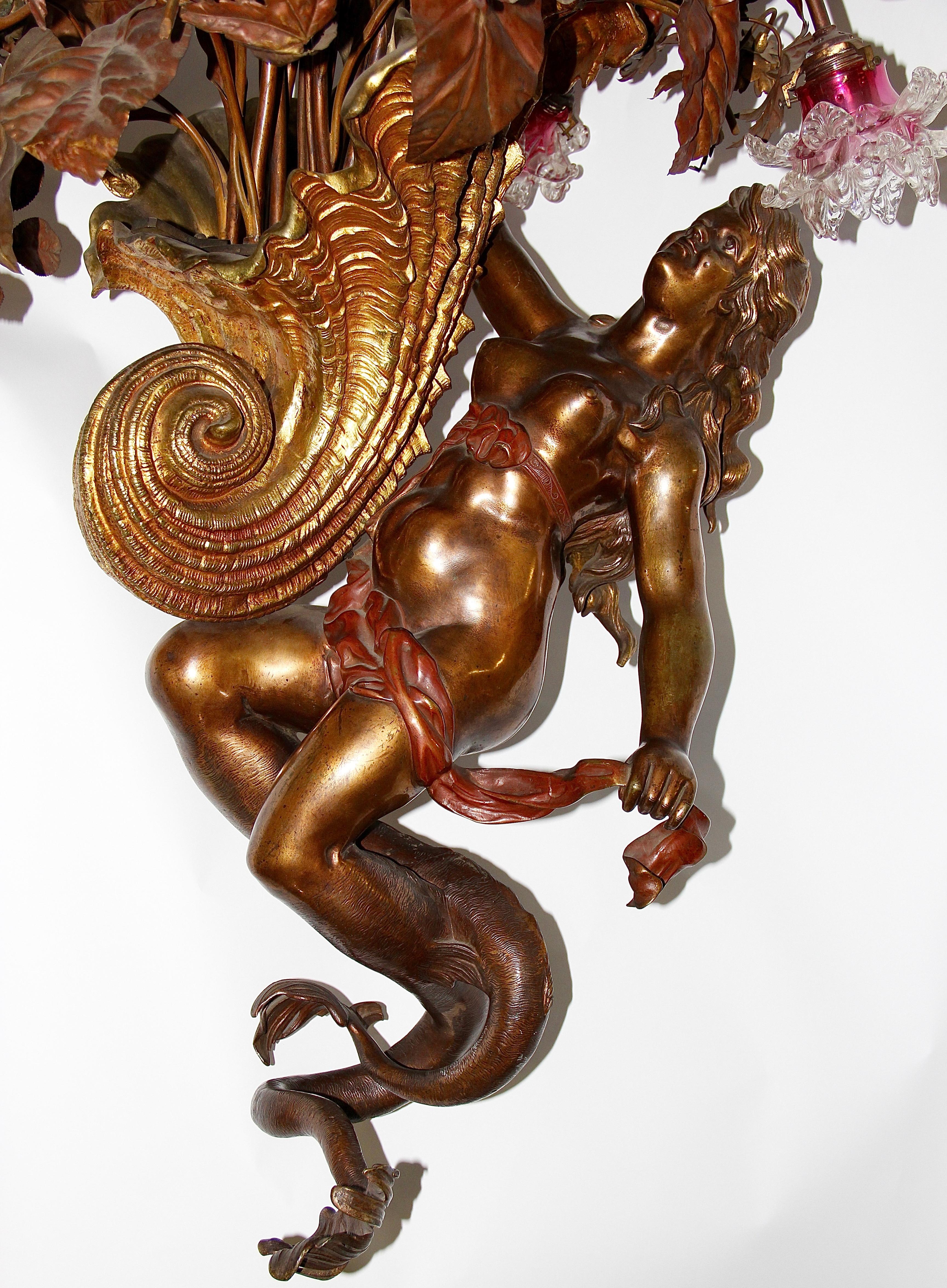Extremely decorative, heavy and high quality chandelier.
Date of origin estimated circa 1880-1920.

This chandelier impresses with its uniqueness.

Large bronze nude figure as a mythical creature (presumably a kind of mermaid) with one hand