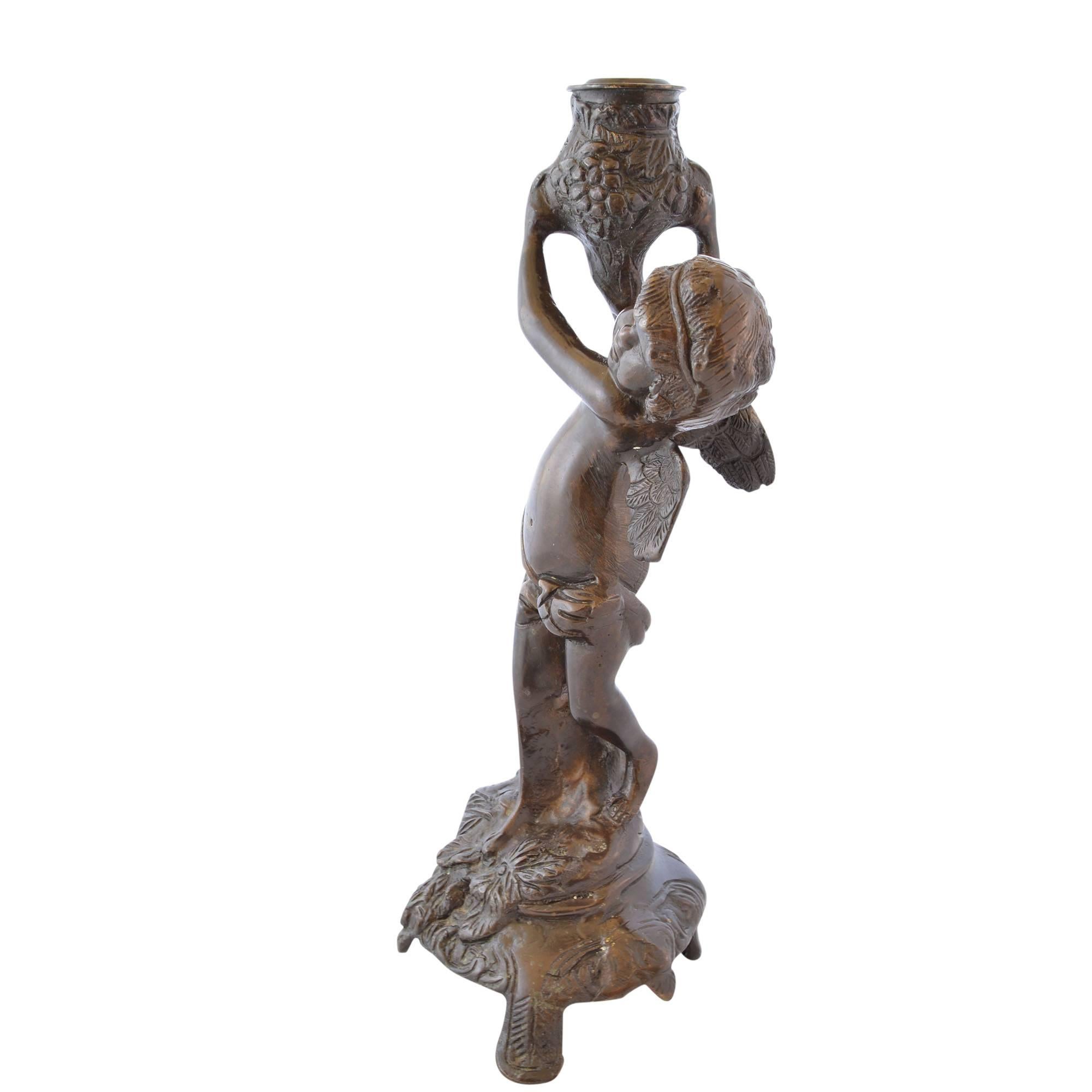 Matched pair of bronze cherub candlesticks. A detailed angel is showcased on each bronze candlestick with wings aloft and leaning against a candle post. The rounded faces and chubby cheeks creates a softness and joyful charm. 

Measures: 11.75
