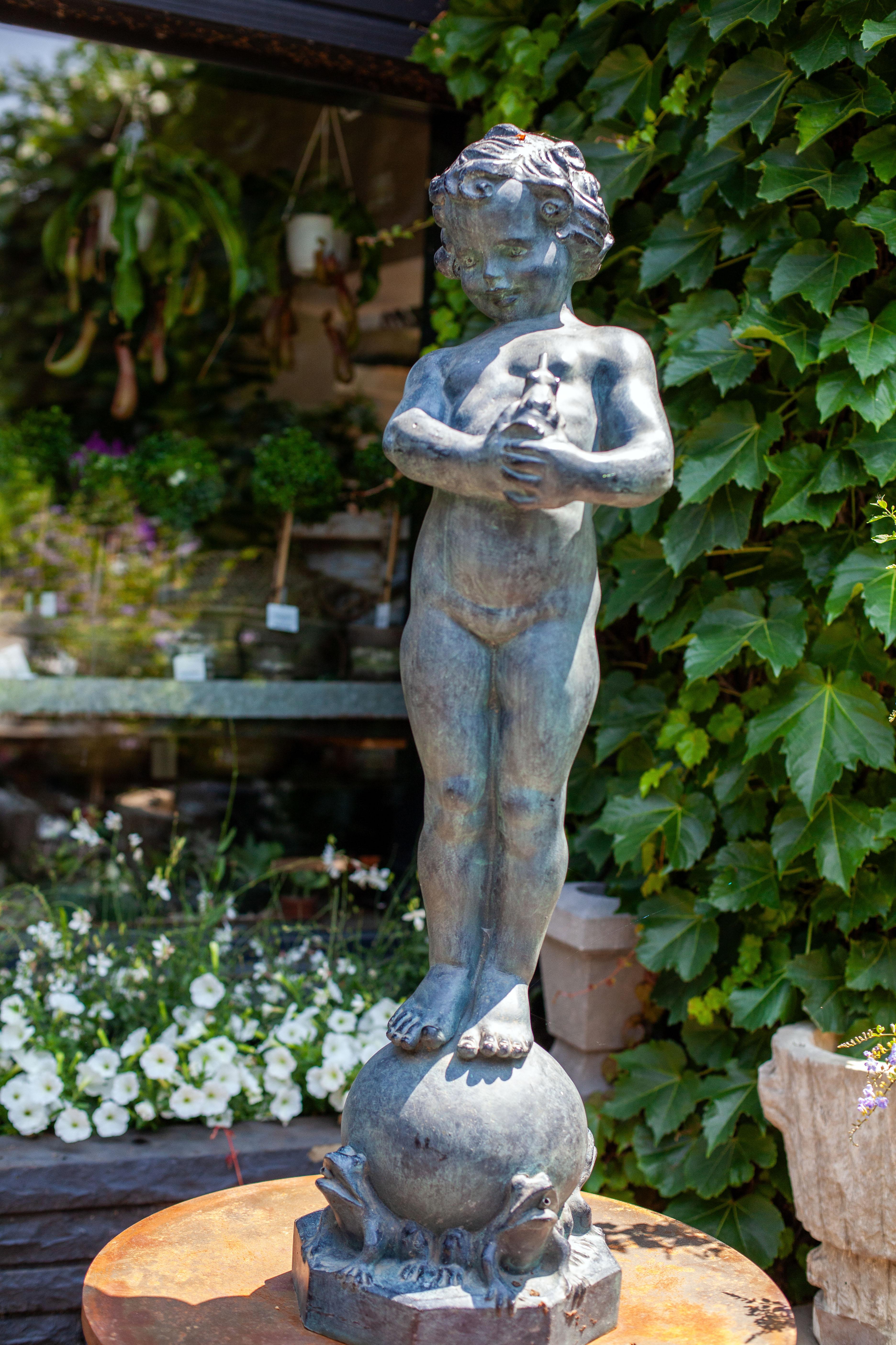 In a tranquil garden bathed in the soft hues of dawn, there stands a captivating bronze statue, a testament to the artistry of a bygone era. This enchanting masterpiece portrays the innocence and wonder of childhood frozen in time.

At its center, a