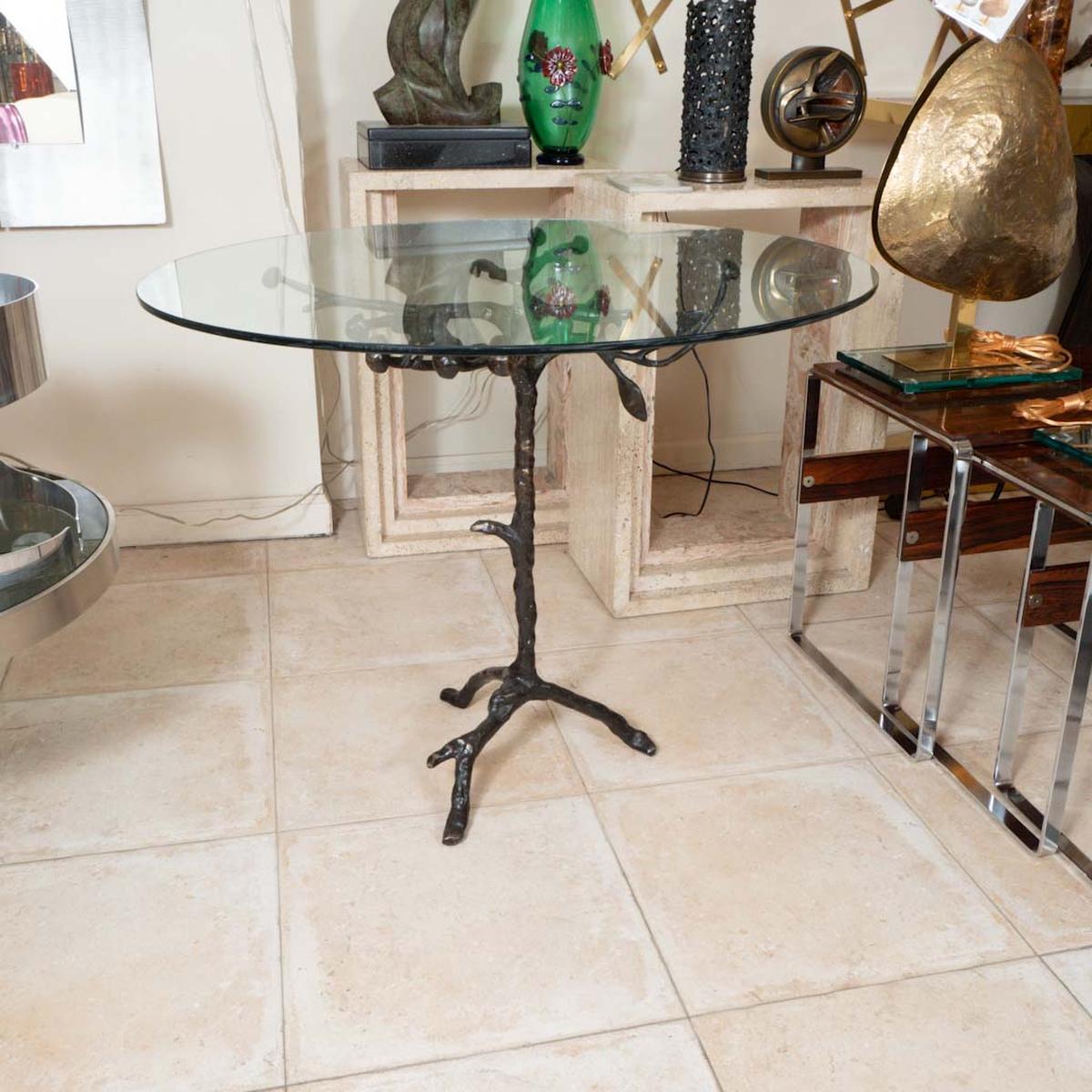 Bronze circular side table with glass top and foliate design.
