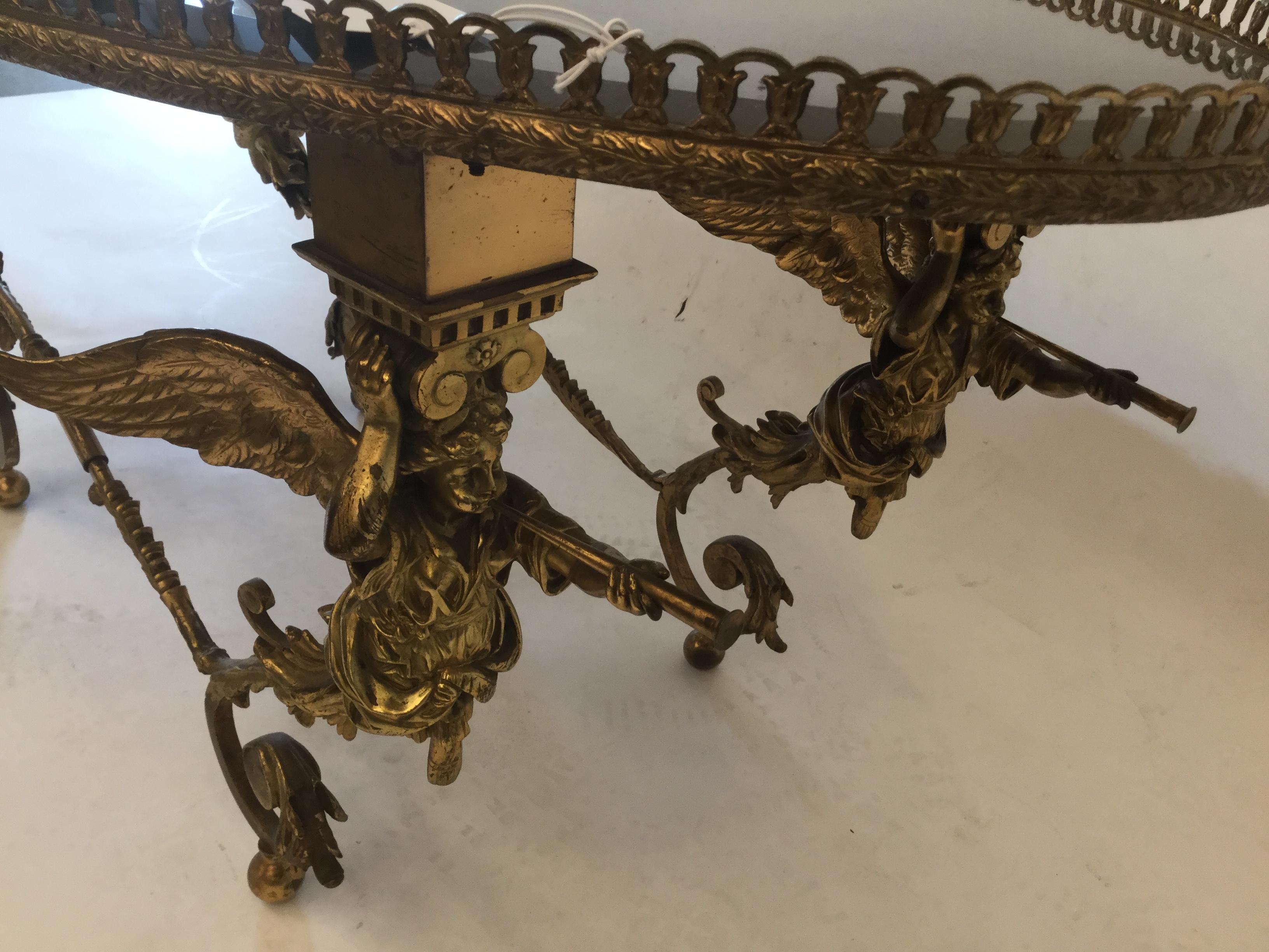 Hollywood Regency style coffee table in bronze with mercury glass top
 The bronze frame depicts four winged full bodied cherubs.

In excellent vintage conditions