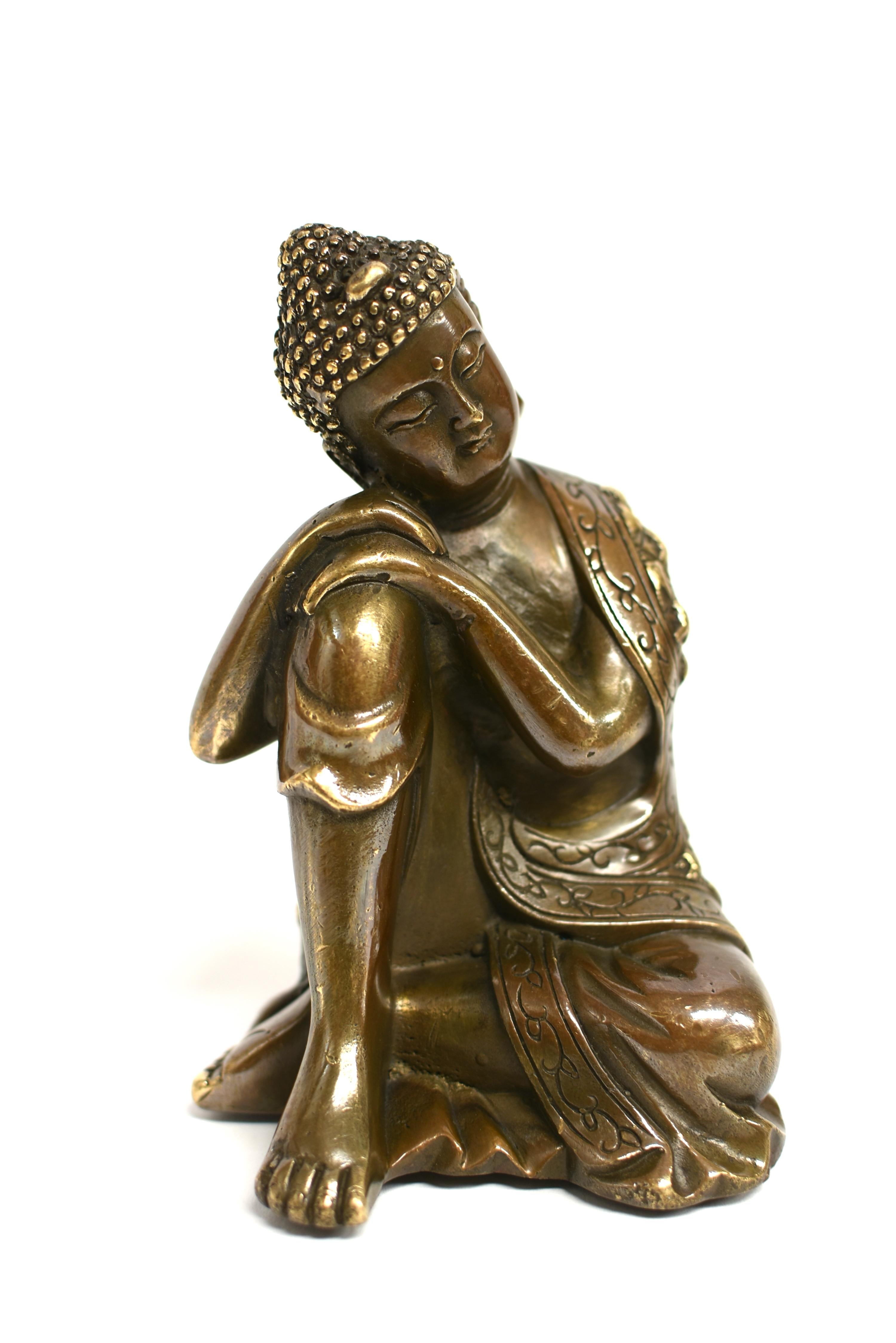 A fine bronze statue depicting Buddha in contemplative mode. The broad face with closed eyes casting a serene aura, framed by long-lobed ears, beneath coiled hair and surmounted by an ushnisha. Buddha wears a long robe falling in graceful folds