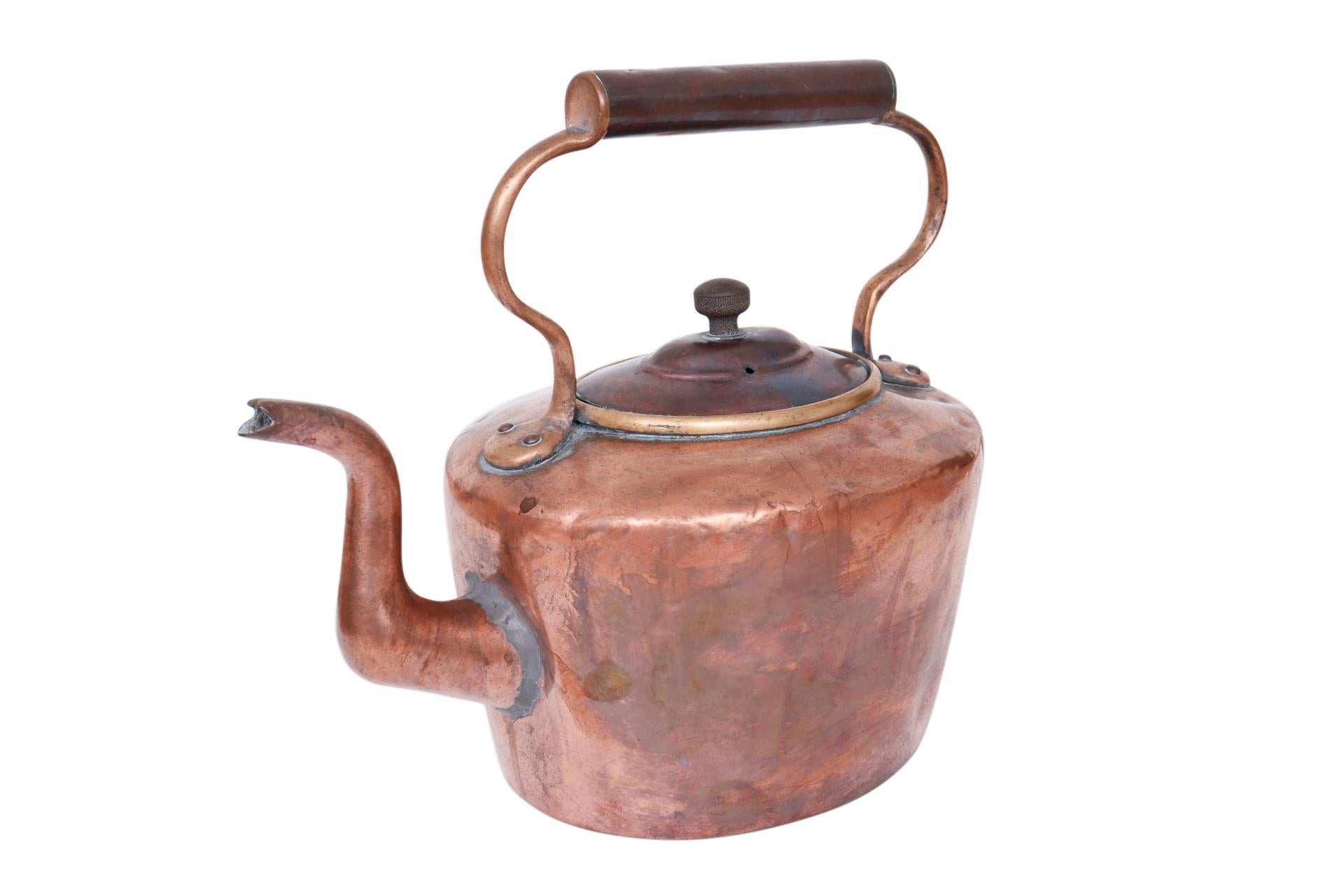 A copper plated brass kettle with bronze lid. The kettle lifts with a copper handle with a bronze handhold. Some copper patina and wear revealing brass can be seen at the joins.