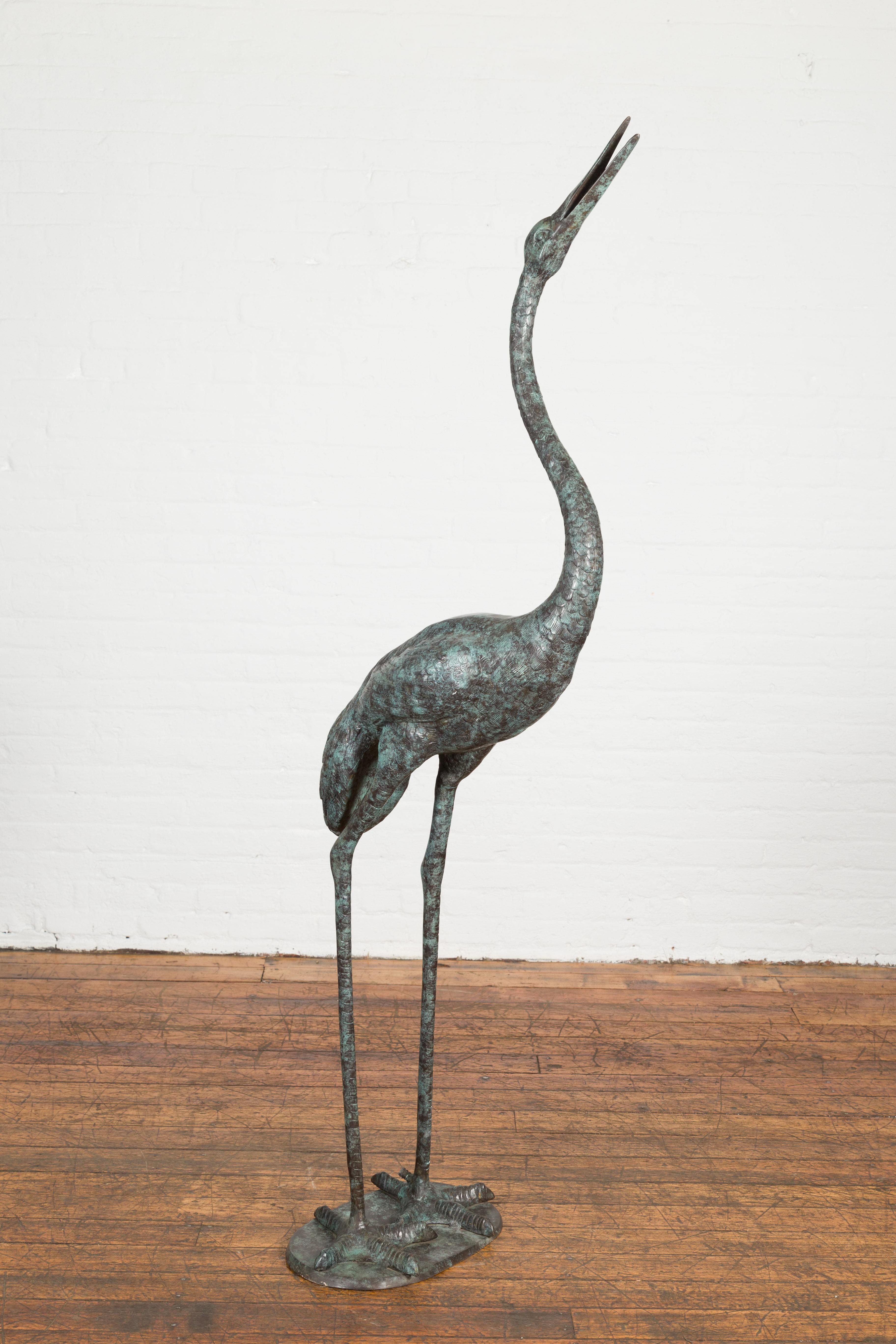 A custom made lost wax cast bronze crane fountain sculpture with verdigris patina, tubed as a fountain. Bring a touch of natural elegance to your outdoor space with this custom-made, lost wax cast bronze crane fountain sculpture. Handcrafted using