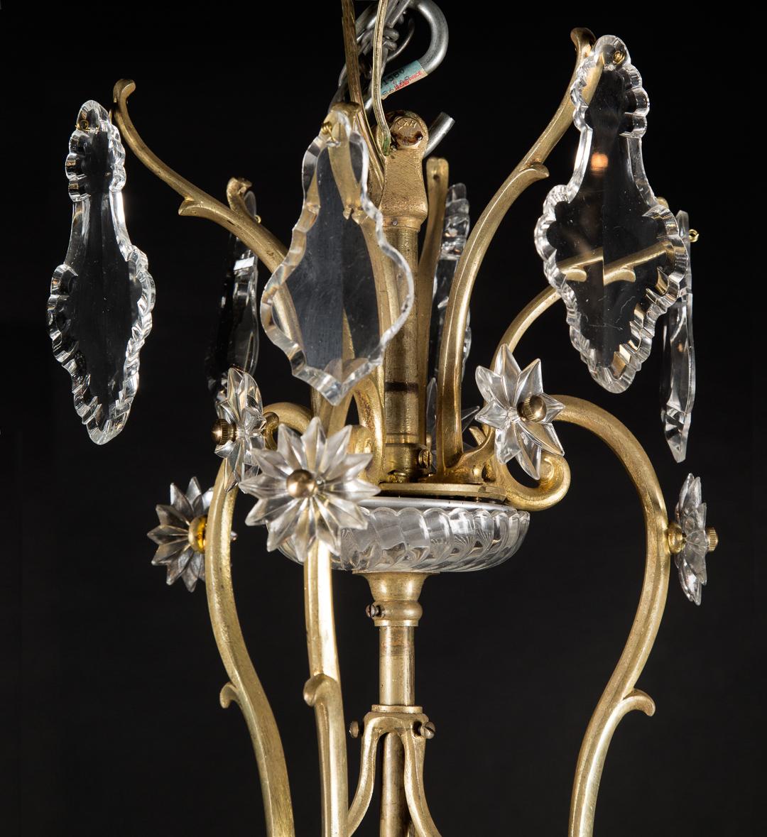 This Louis XV bronze chandelier is draped with beautifully cut crystal plaquettes and crystal stars as well as a crystal bowl at top and bottom. The French antique piece dates back to the late 19th century and plays host to a bird cage shape,