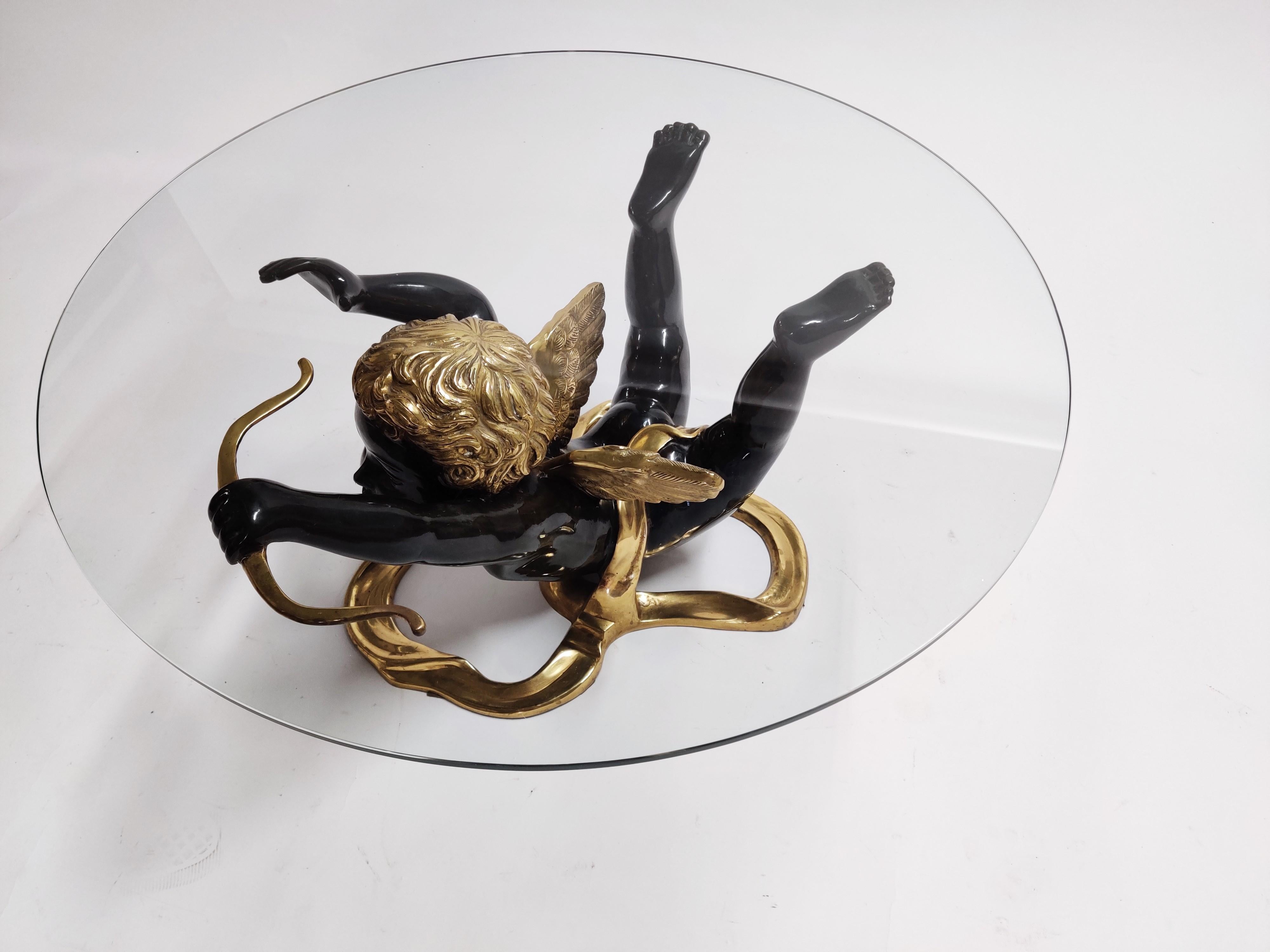 Brass coffee table with a cupid sculpture base.

This beautifully crafted and elegant coffee table comes with a round glass top.

Heavy quality.

1970s, Belgium

Dimensions:
Table:
Diameter 85cm/32.5