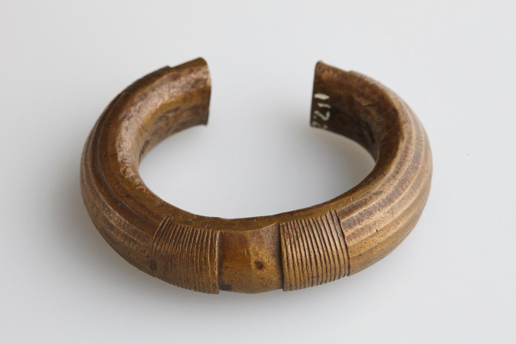 19th-century bronze currency bracelet / Manilla in horseshoe form with fixed opening. Intricate graphical design with lines and accent points on the top and at both tips. This type of bracelet was worn or used by the Baoule and Dogon People, who are
