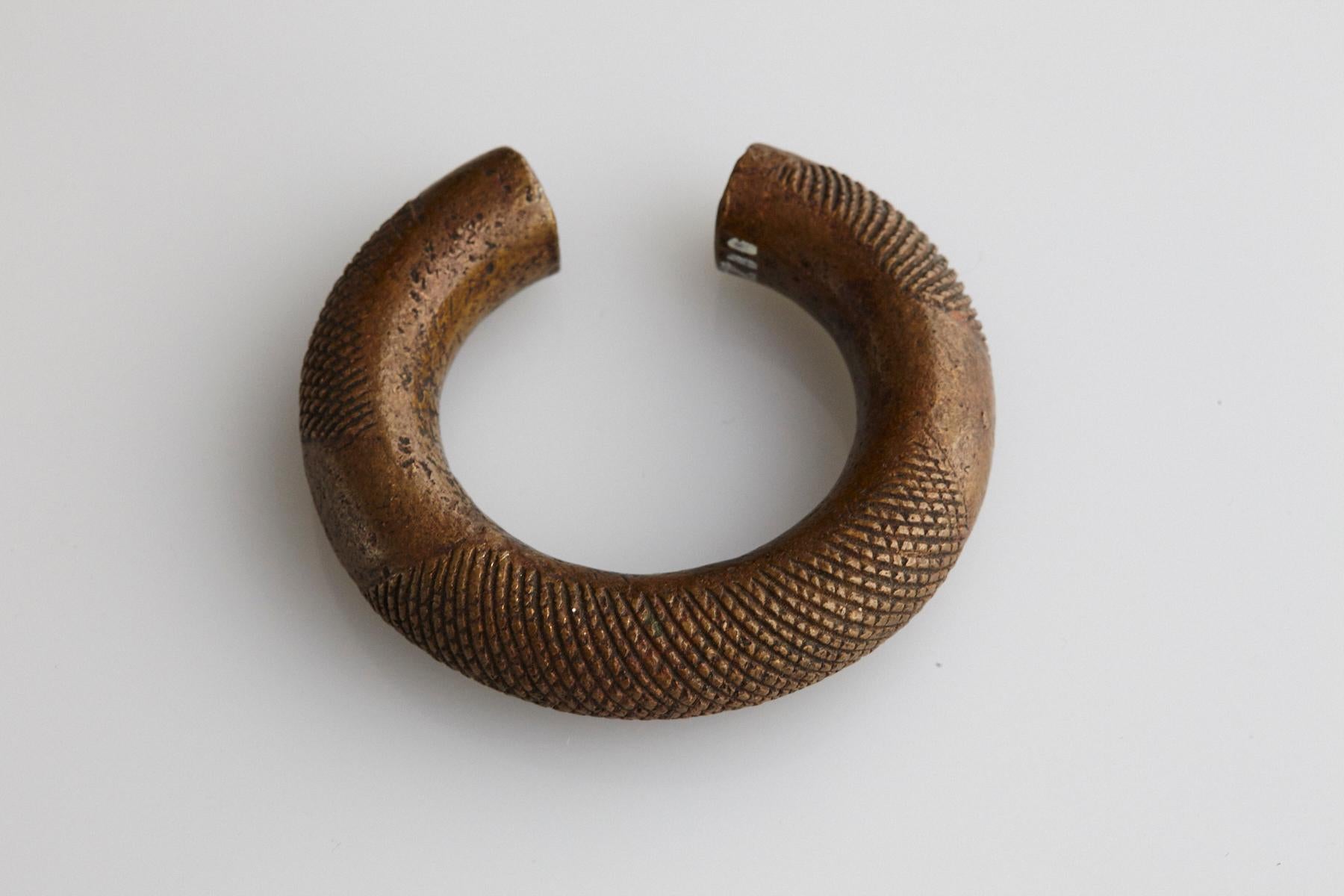 19th-century bronze currency bracelet / Manilla in horseshoe form with fixed opening. Intricate graphical design with a lattice pattern. This type of bracelet was worn or used by the Baoule and Dogon People, who are living in Burkina Faso and Cote