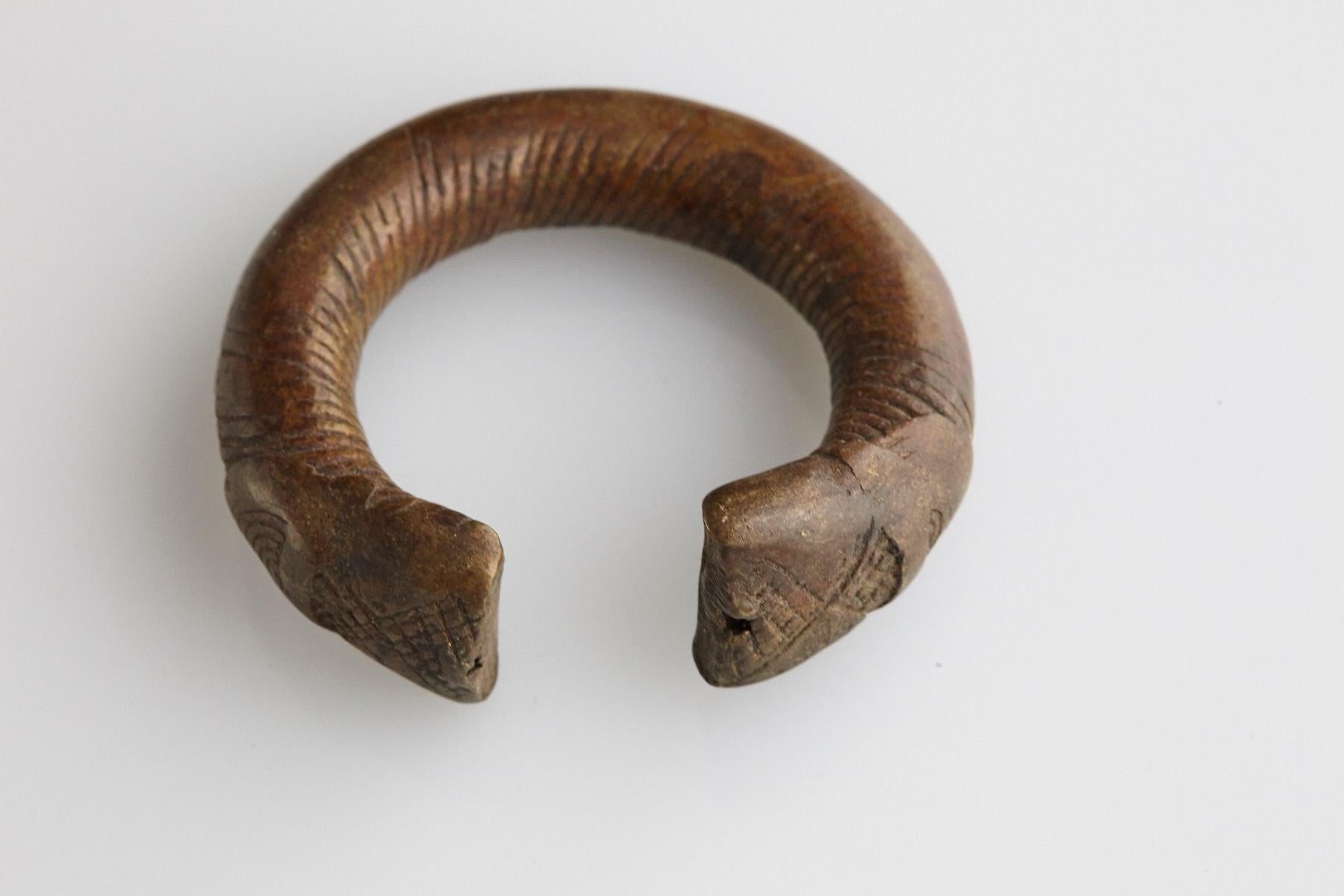 19th-century bronze currency bracelet / Manilla in horseshoe form with fixed opening. Intricate graphical swirl design and tips are shaped with large flat ends with cross pattern designs. This type of bracelet was used and worn by the Baoule and