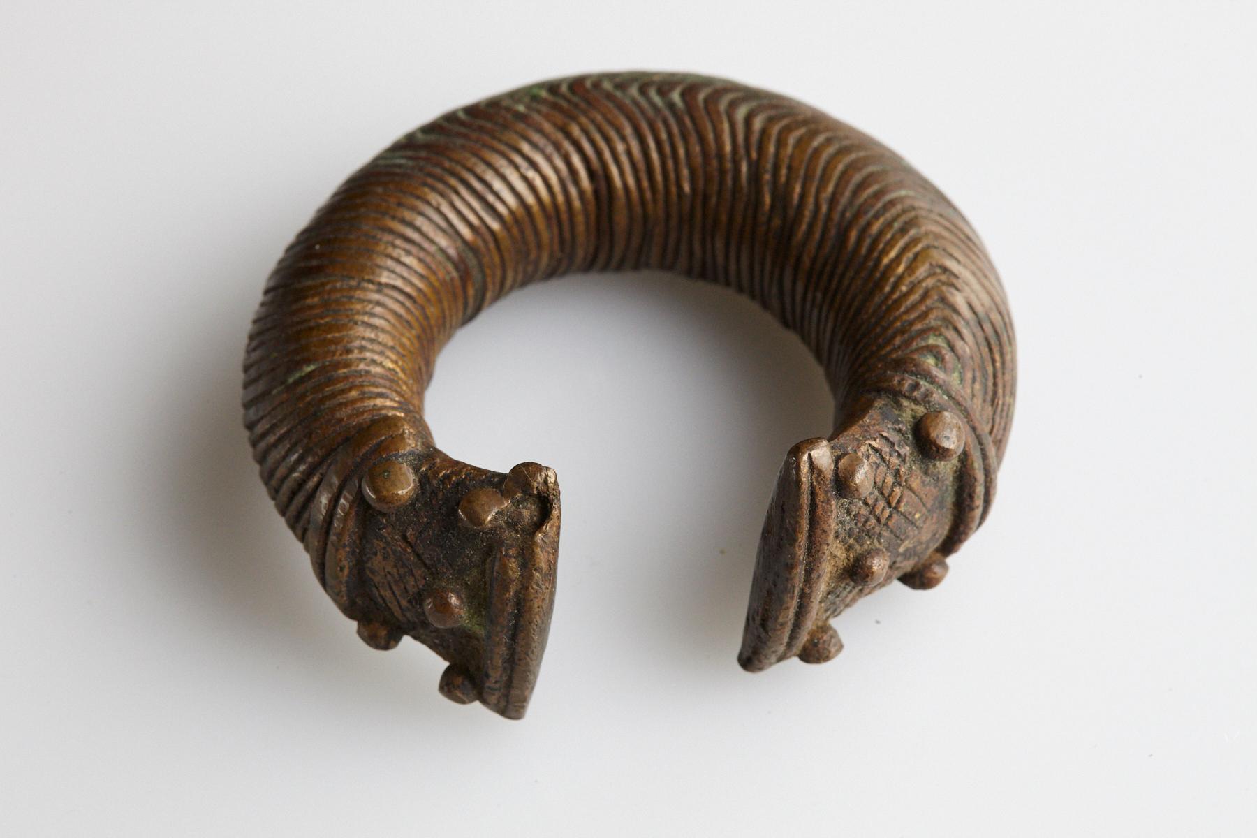 19th-century bronze currency bracelet / Manilla in horseshoe form with fixed opening. Intricate graphical swirl design and tips are shaped with large flat ends with 5 beads on each side. This type of bracelet was worn by the Baoule and Dogon People,