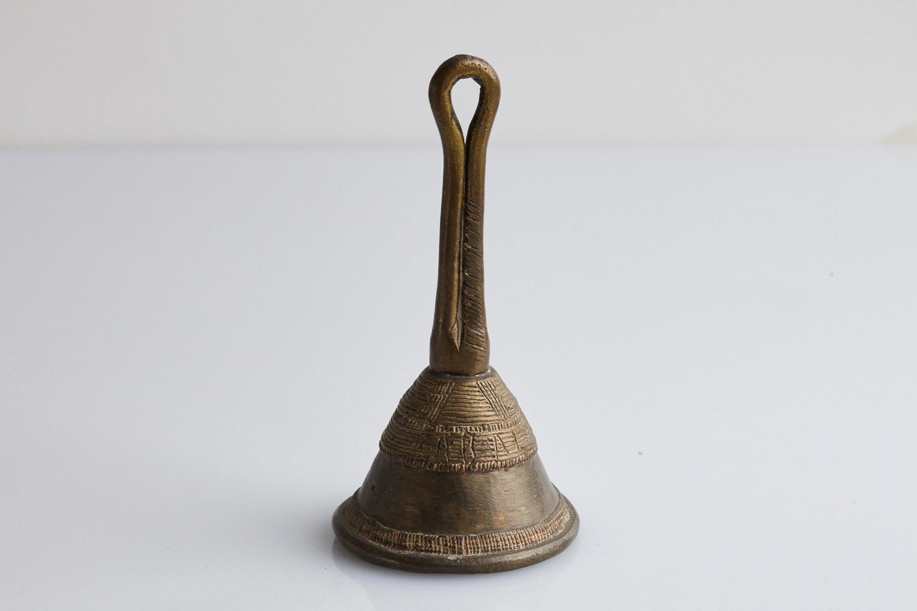 Bronze Dan (also called Yakuba) bell, Cote d'Ivoire, circa 1960s.
This Dan bell is made from the lost-wax process. It has a looped handle and stylized designs on the bell and around the rim.

The numbers are the inventory numbers from Penn State