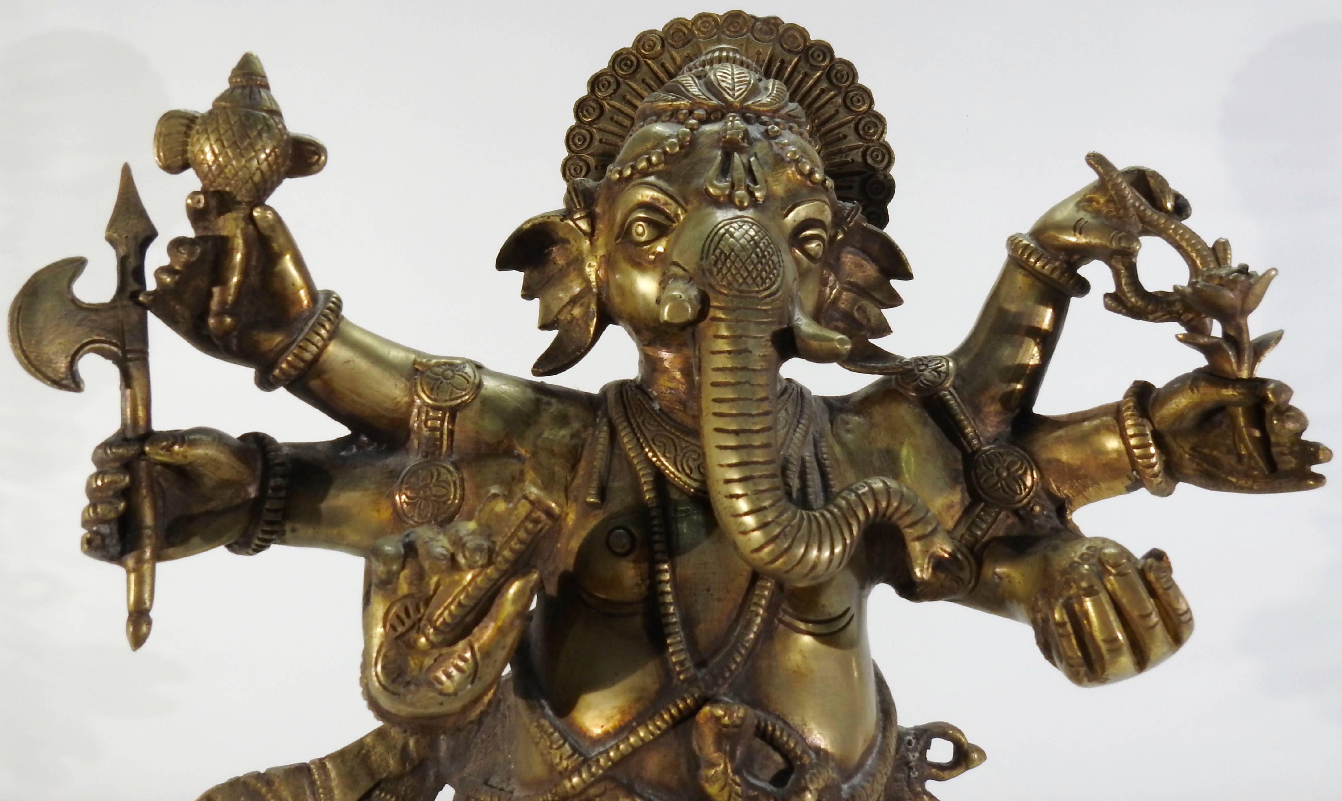 This is a stunning bronze statuette of Ganesha. This detailed statuette depicts Ganesha, the Hindu god of success dancing, with a rat at his feet. He symbolizes all-pervasiveness. He is elaborately dressed and holding a unique treasure in each of