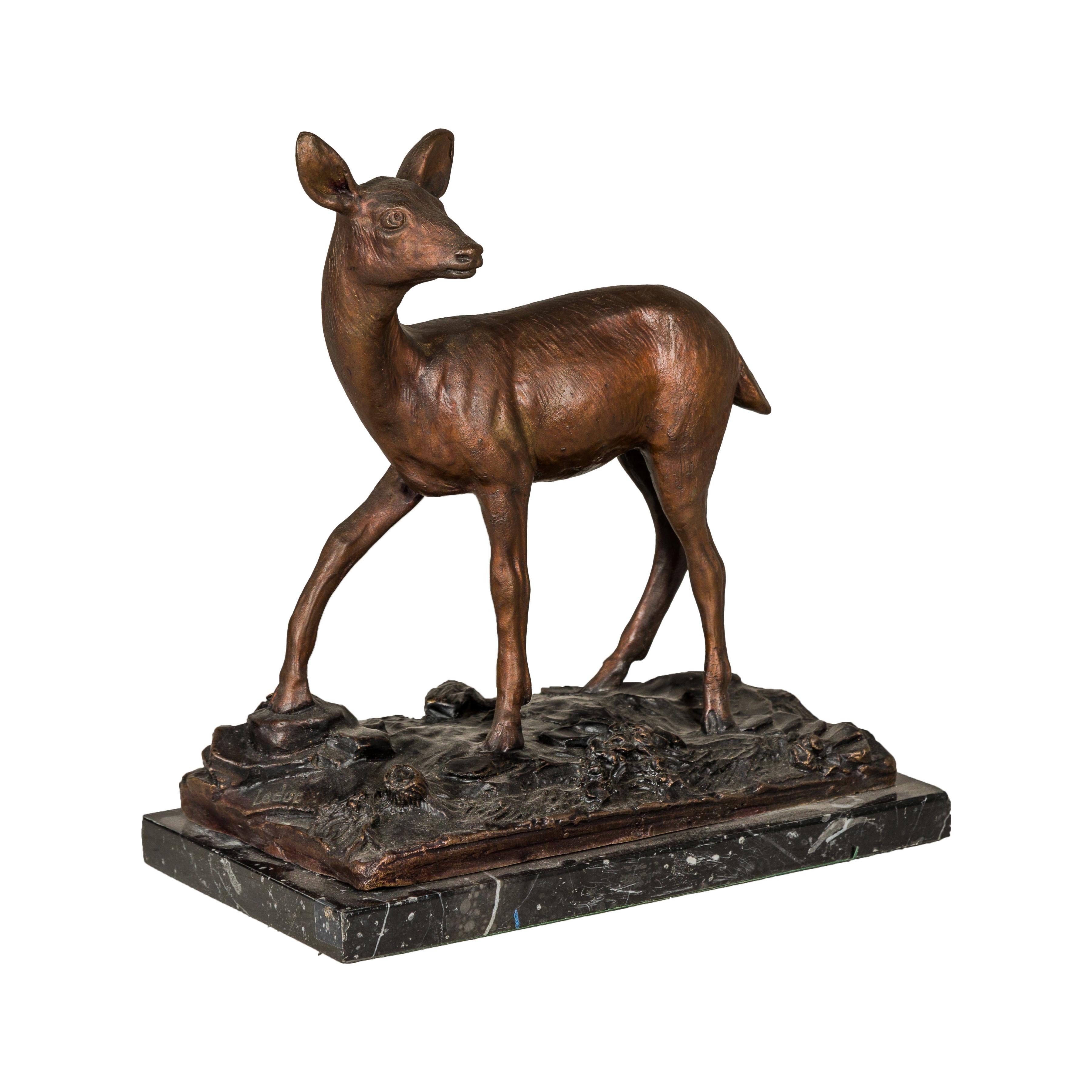 A vintage bronze deer sculpture mounted on a bronze and black marble base. This vintage bronze deer sculpture, elegantly mounted on a unique base that combines bronze and black marble, is a magnificent blend of artistry and natural elegance. The